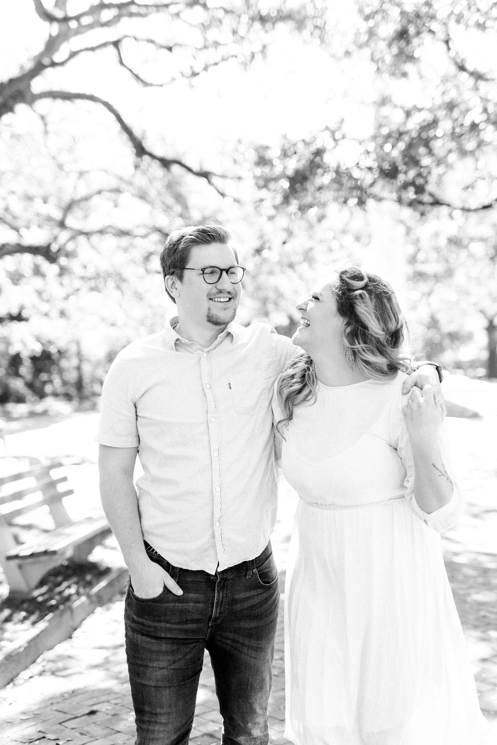 woman laughs at husband with his arm around her shoulders during downtown Charleston anniversary portraits