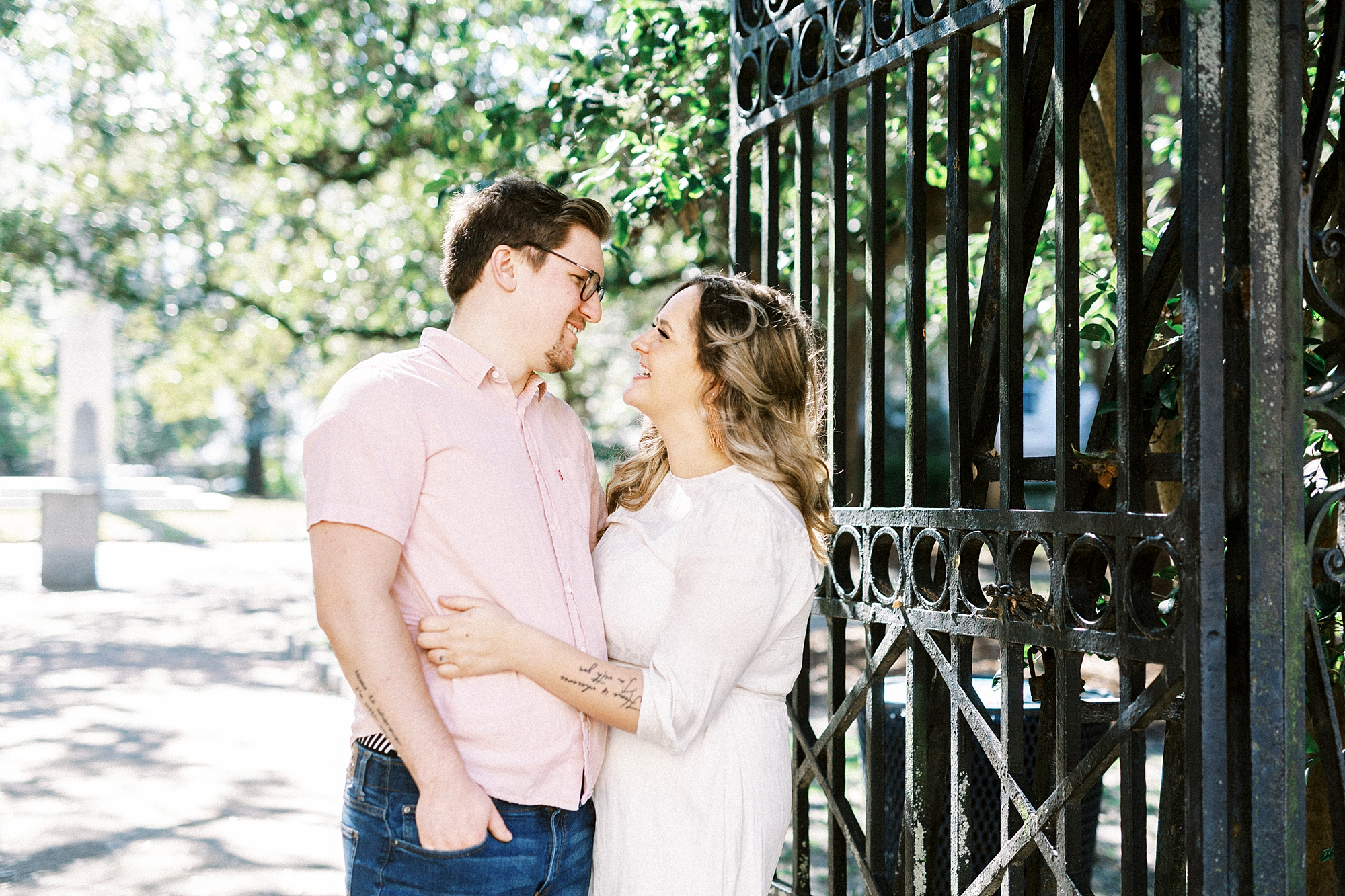 bride and groom smile together by wrought iron gate during downtown Charleston anniversary portraits