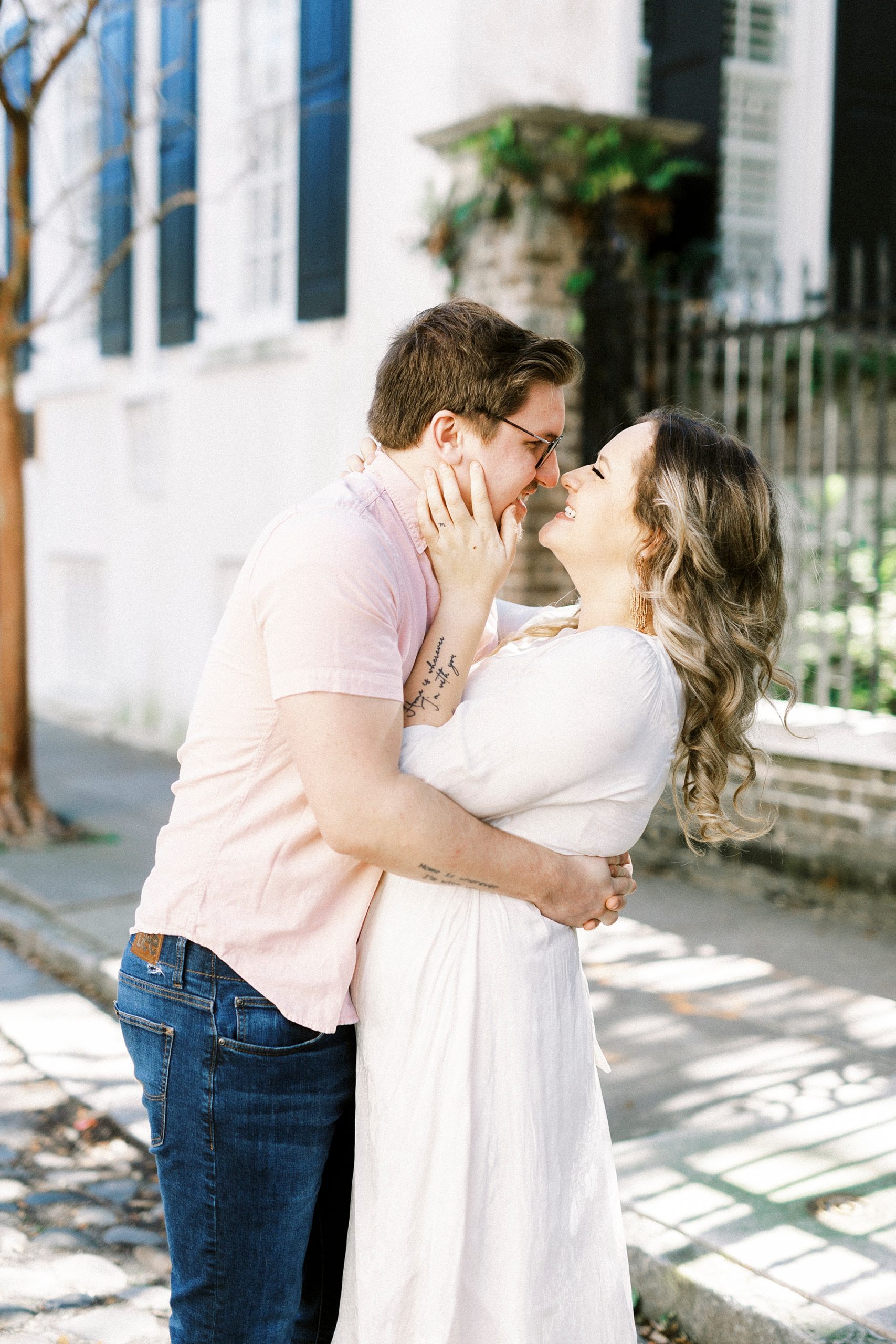 couple stands together on sidewalk in downtown Charleston
