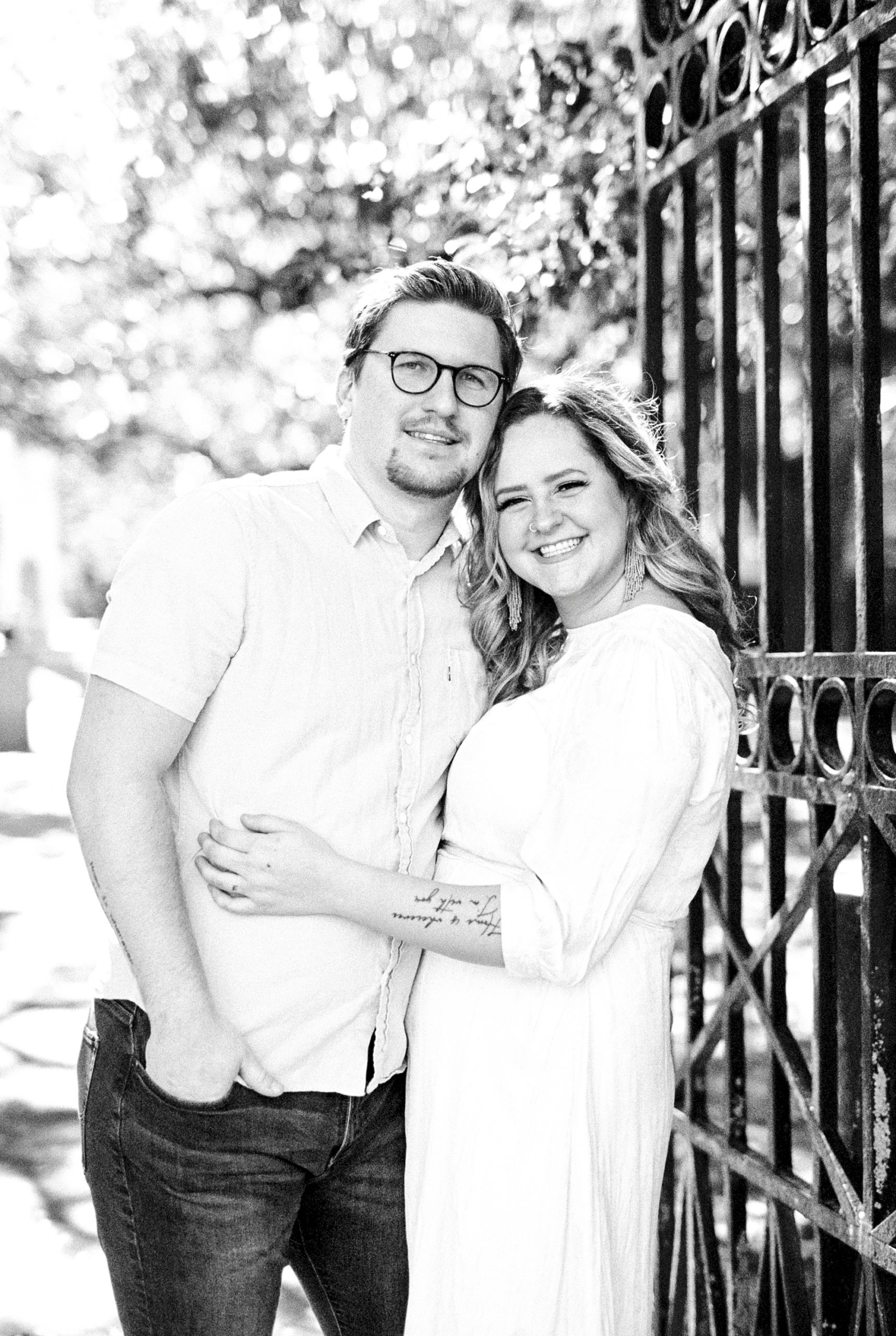 couple poses by wrought iron gate in Charleston SC