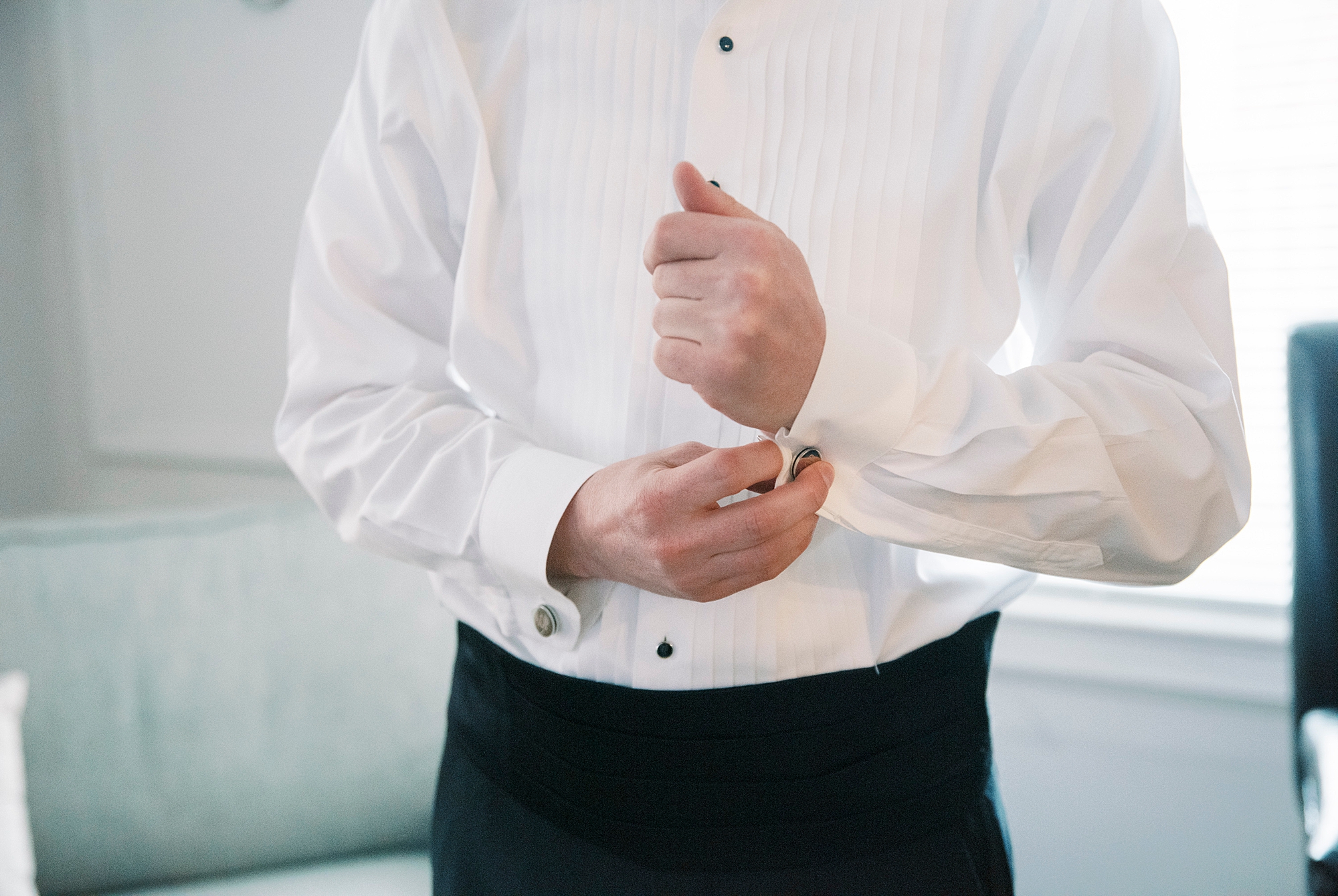 groom adjusts cufflinks before wedding day