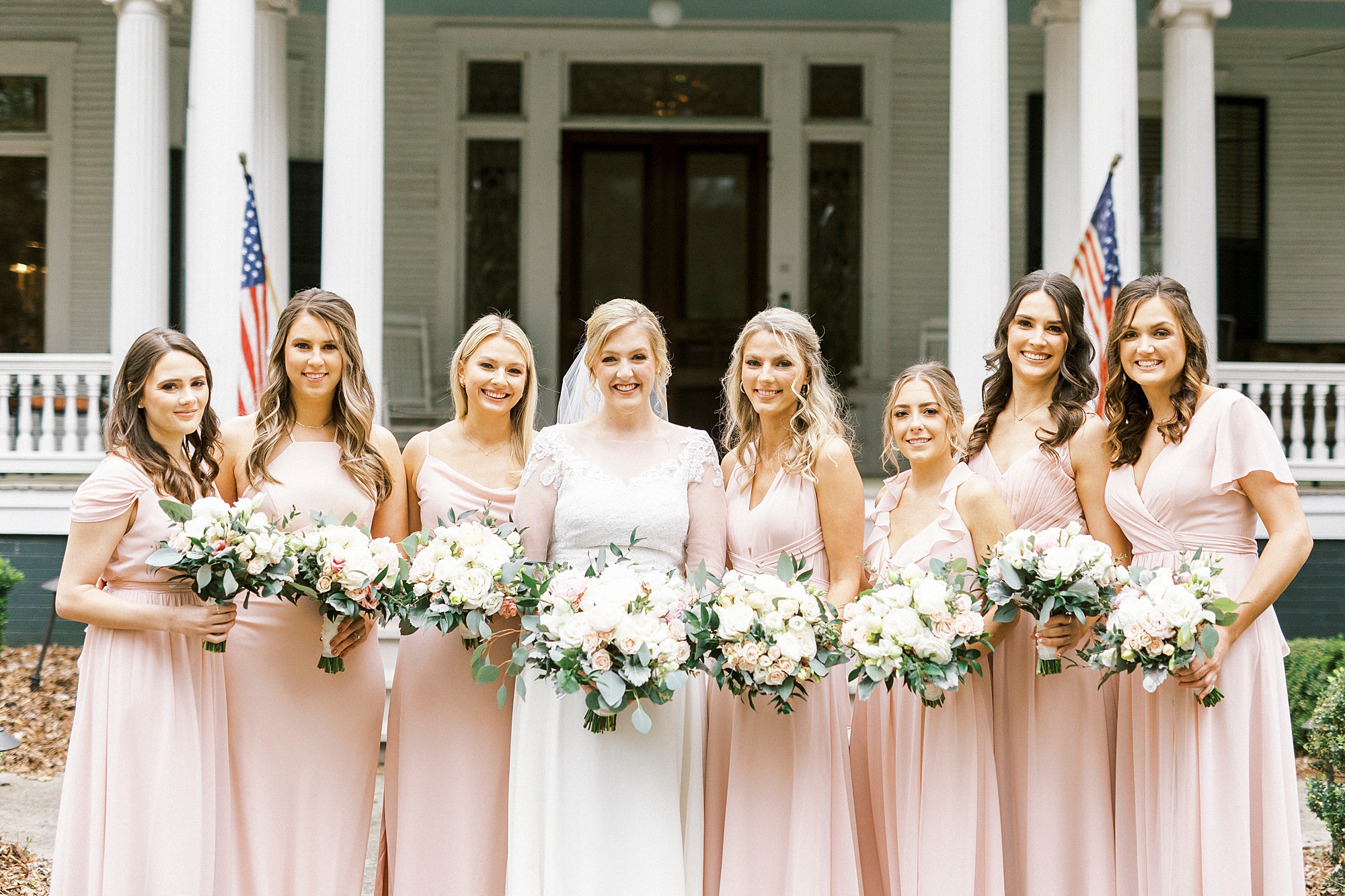 bride stands with bridesmaids in pink gowns