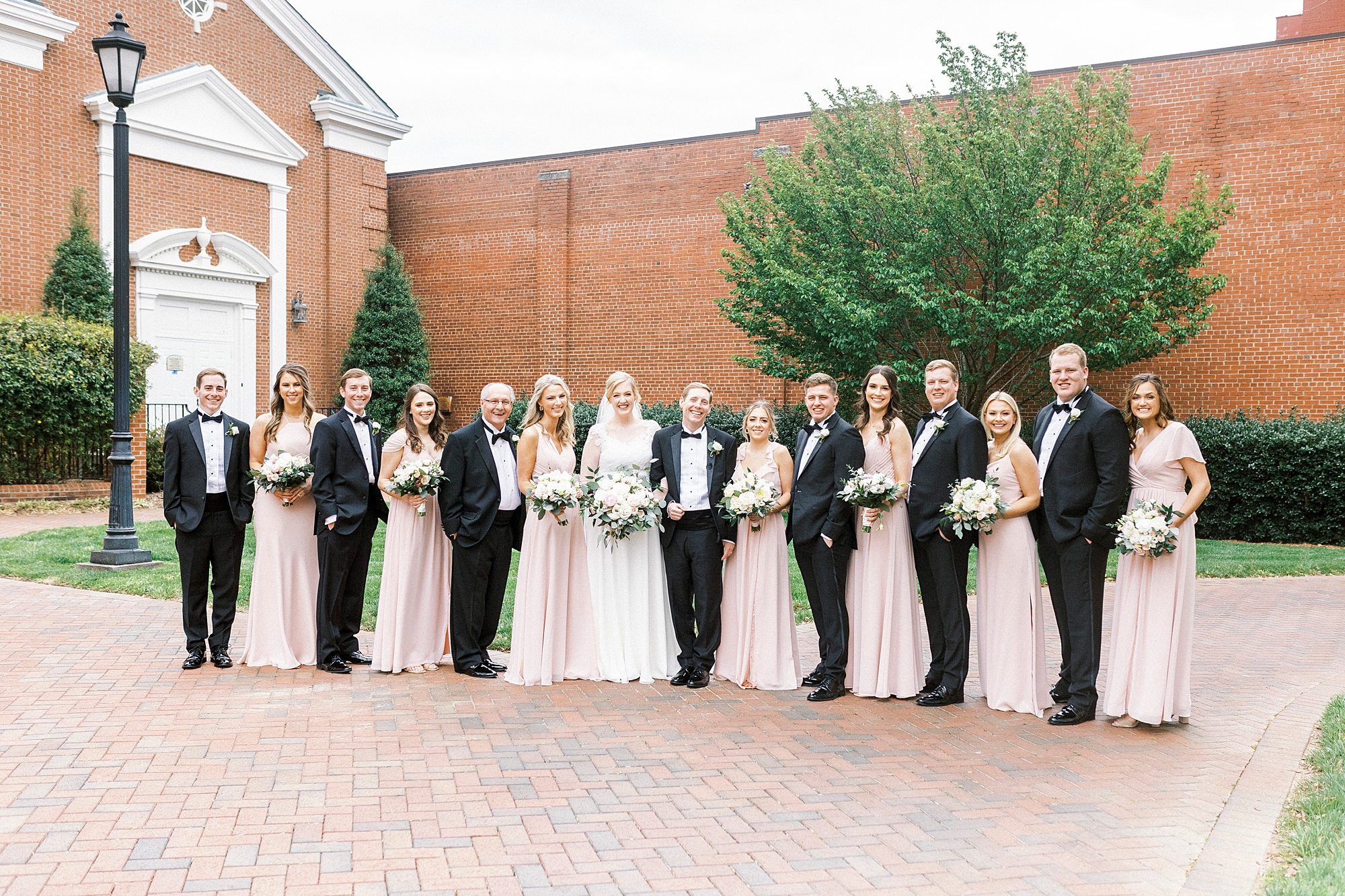 newlyweds pose with wedding party in pink and black