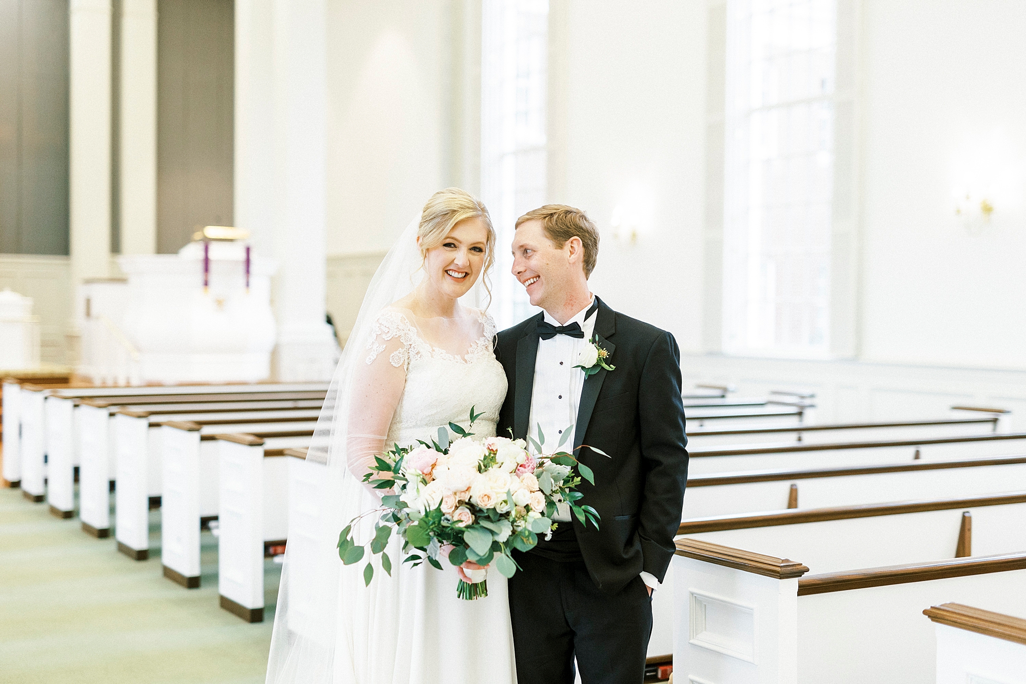 bride and groom smile among pews