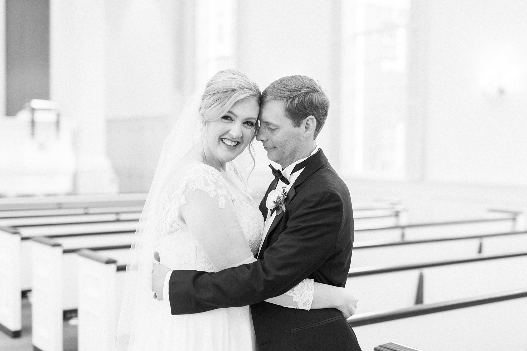 newlyweds hug near pews of the church 