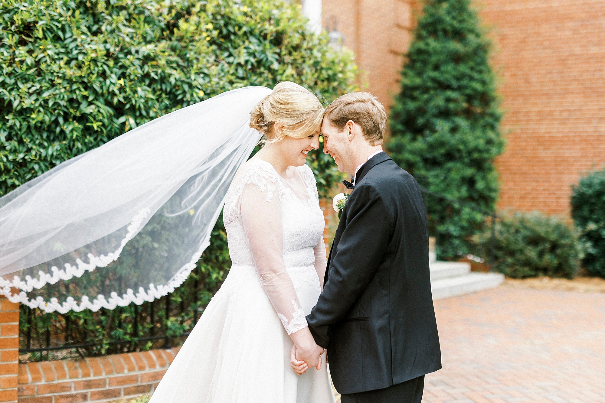 couple leans heads together as veil floats 