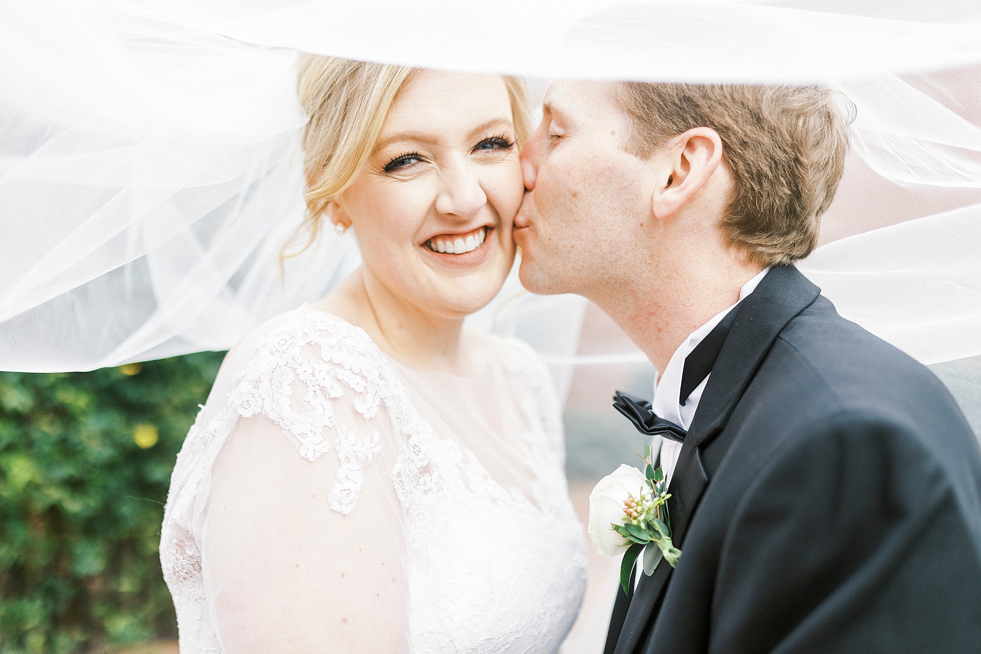 groom kisses bride's cheek during NC wedding photos