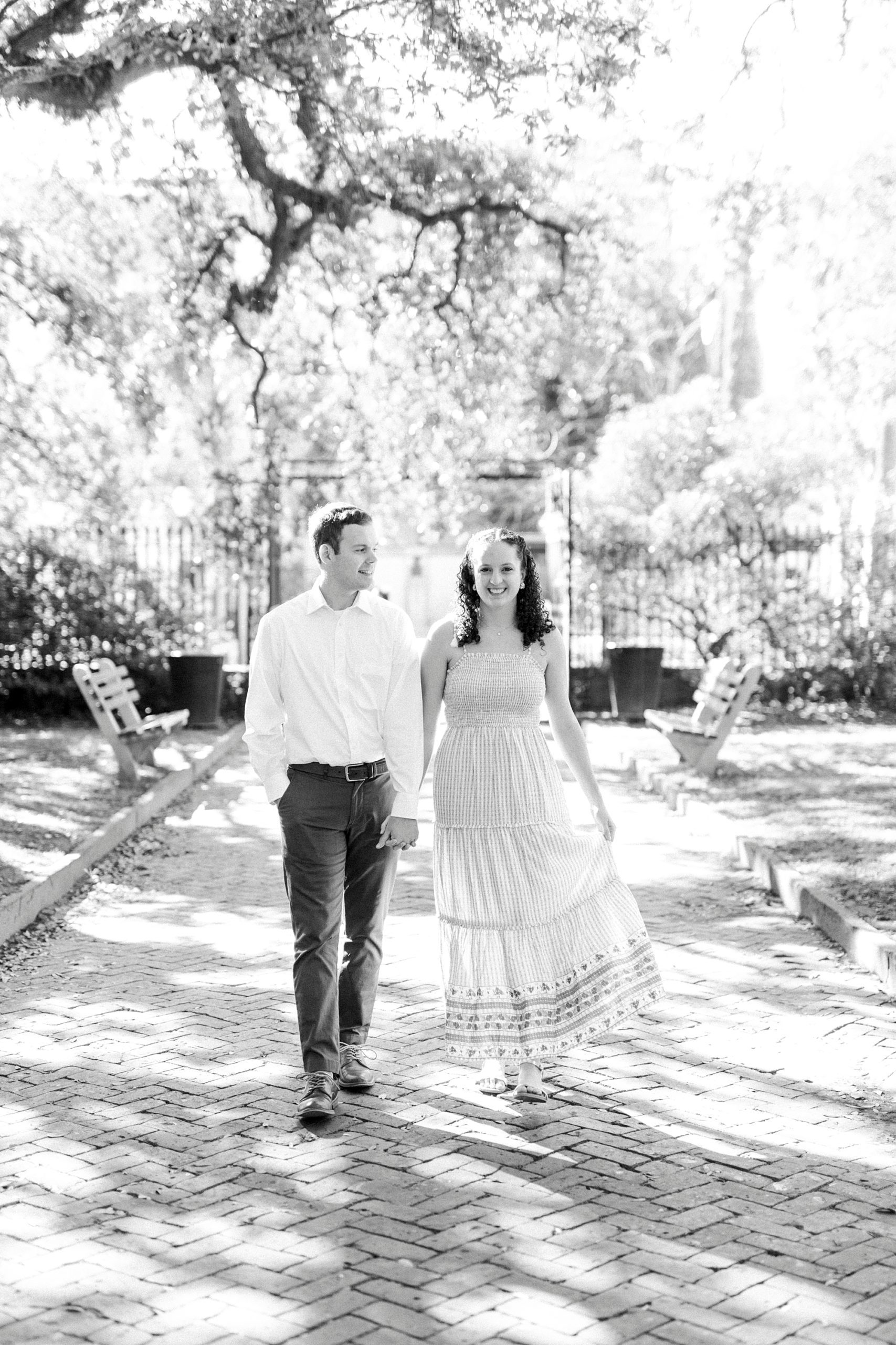 husband and wife holds hands walking through Washington Park