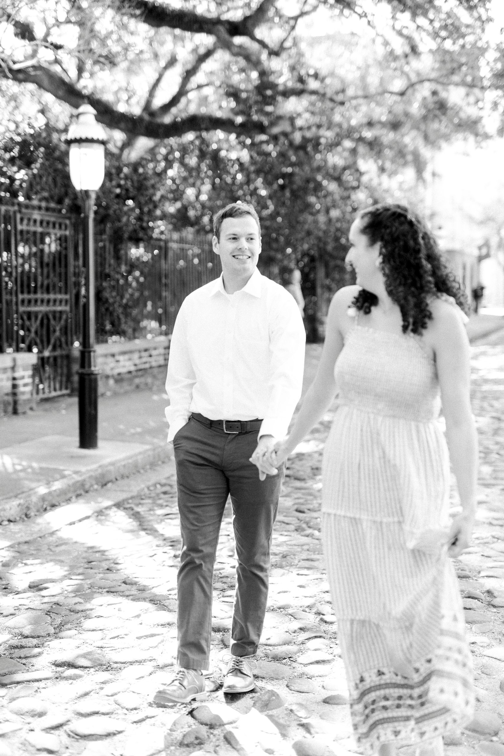 married couple holds hands walking through Charleston park