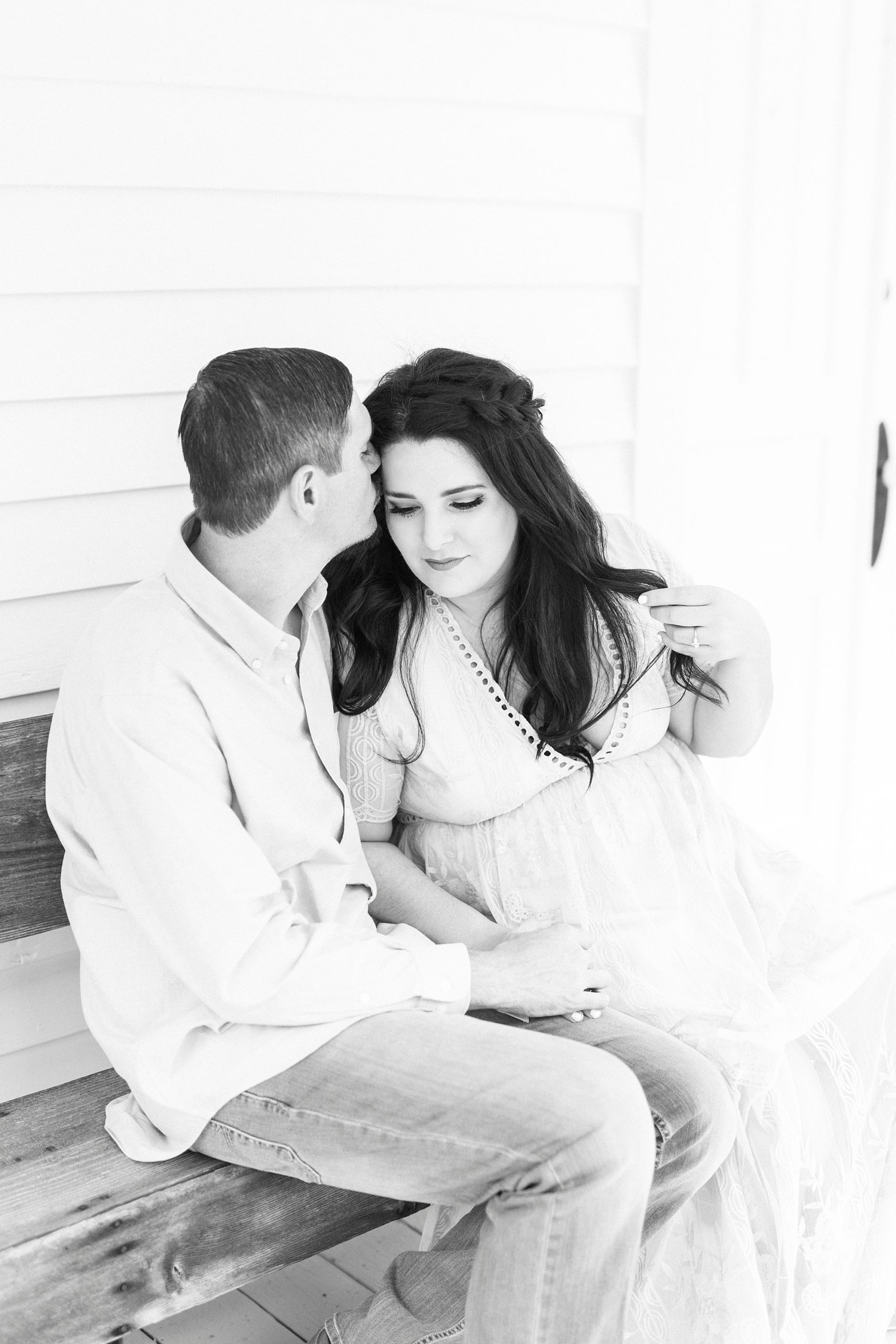 groom kisses bride's forehead outside white chapel