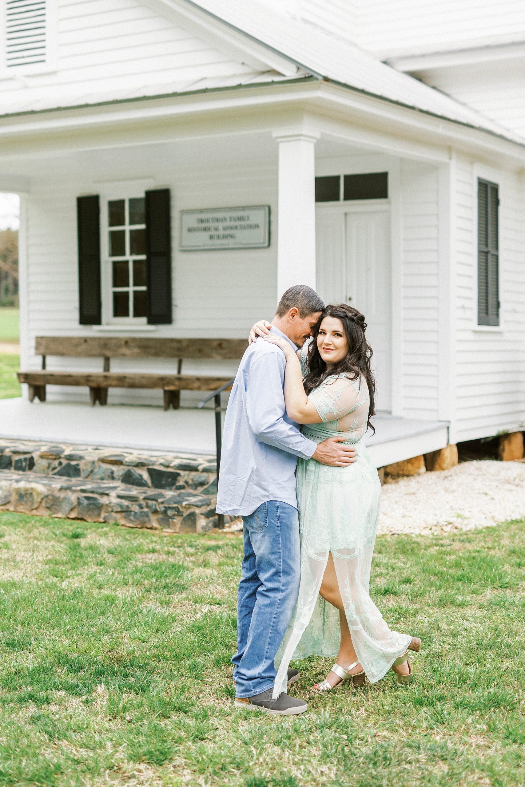 engaged couple hugs outside white chapel in Troutman NC
