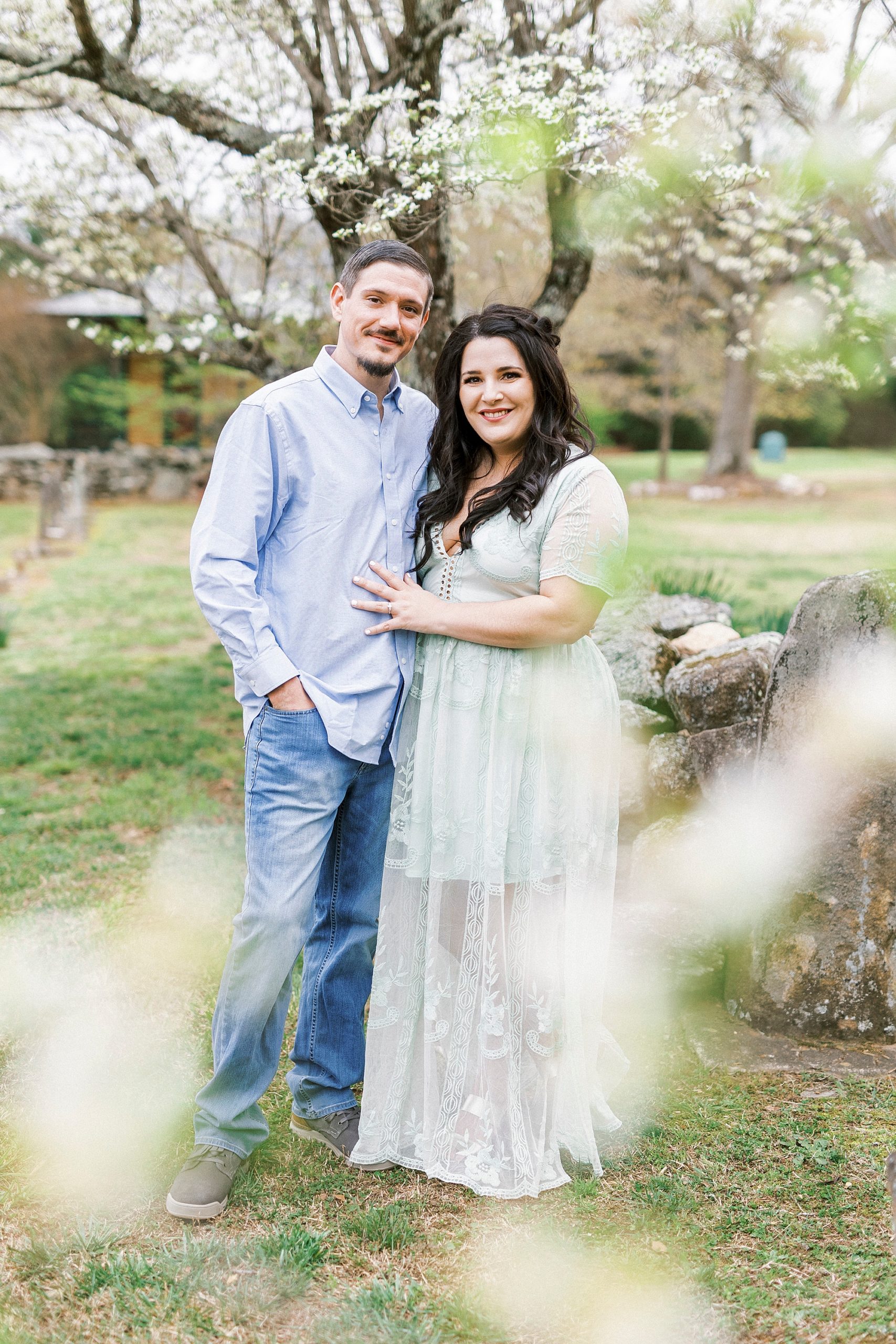 engaged couple lean against stone wall