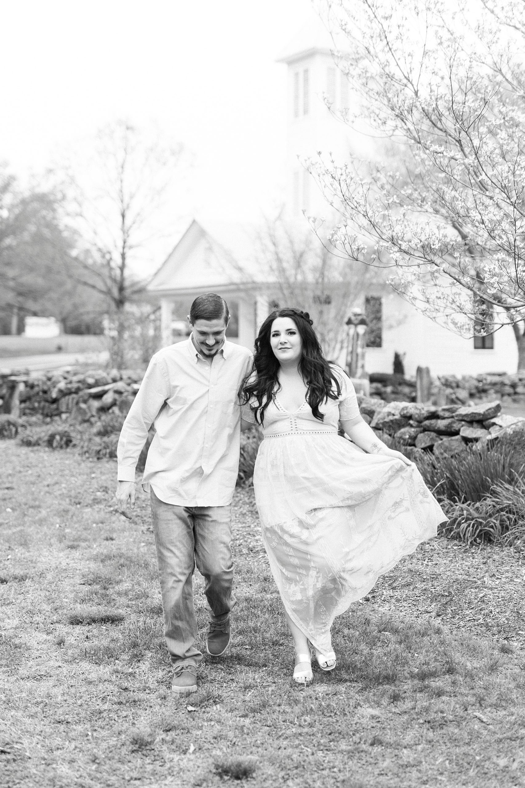 bride moves skirt around while walking outside white chapel 
