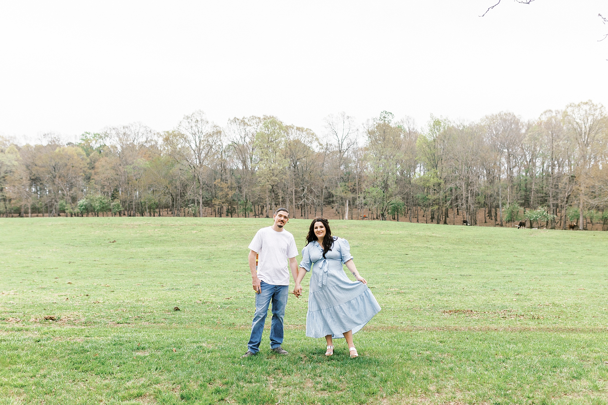 bride and groom hold hands standing in open field