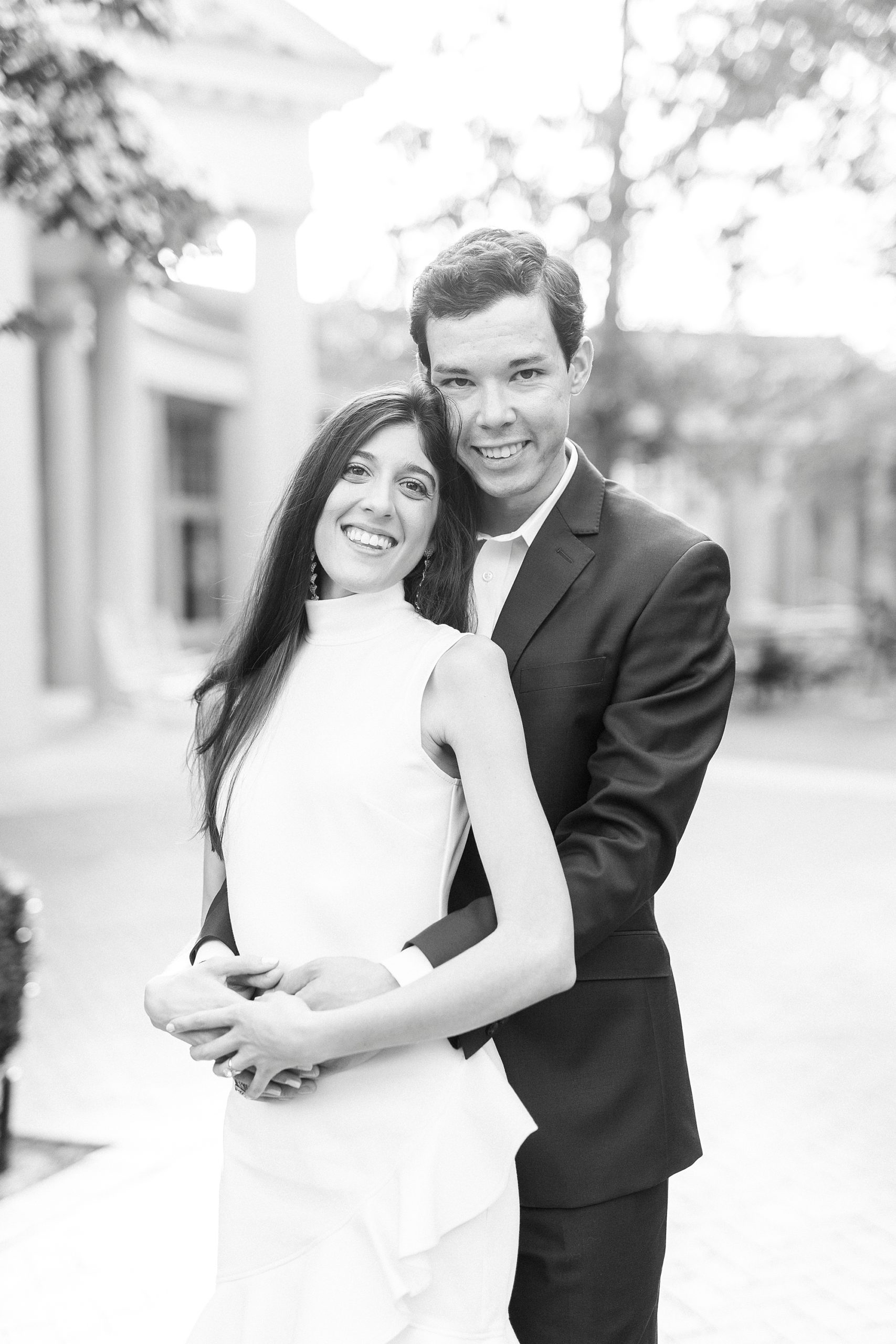 bride leans against groom's chest during photos at Queens University