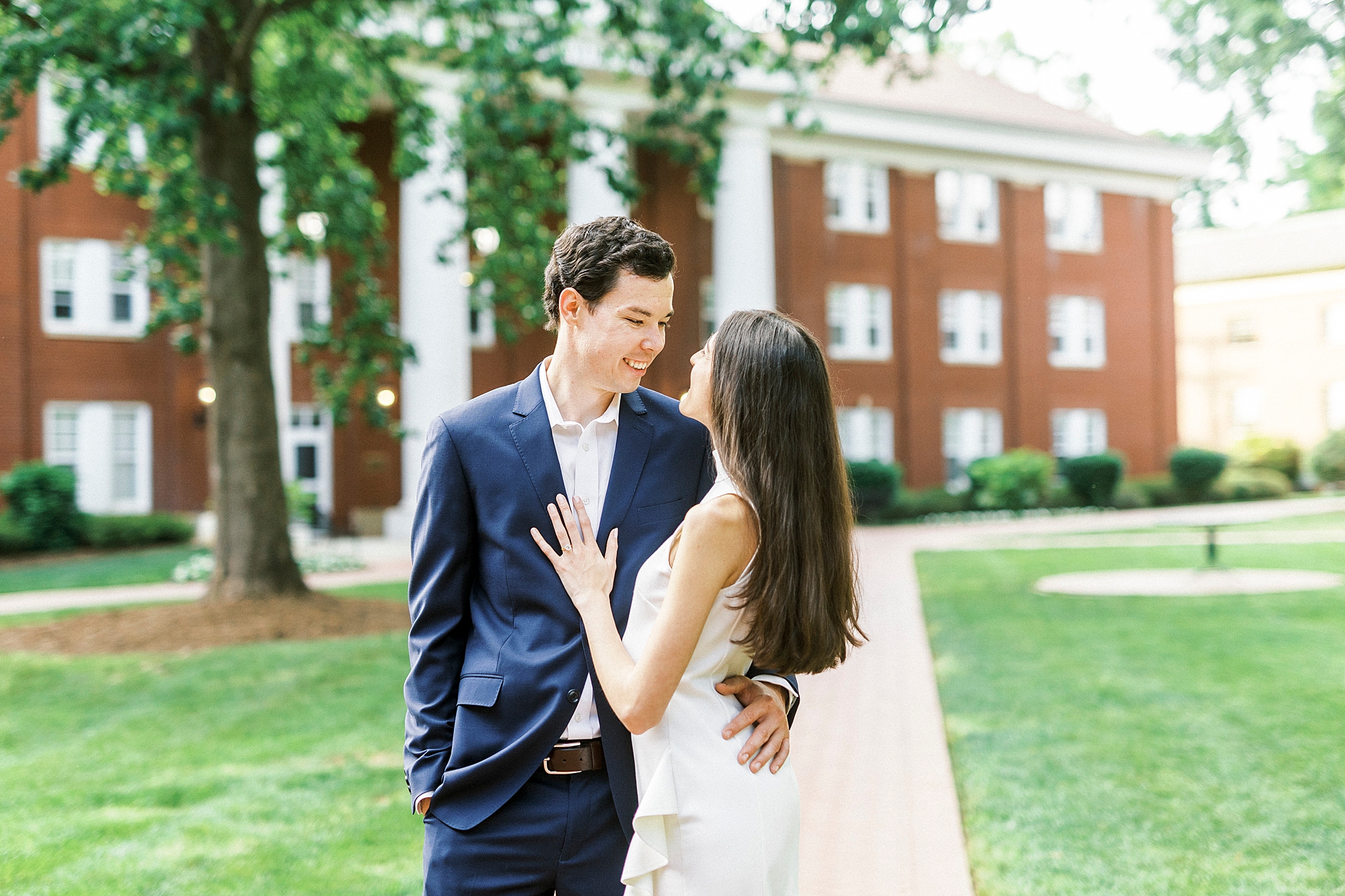 bride puts hand on groom's chest and looks up at him at Queens University