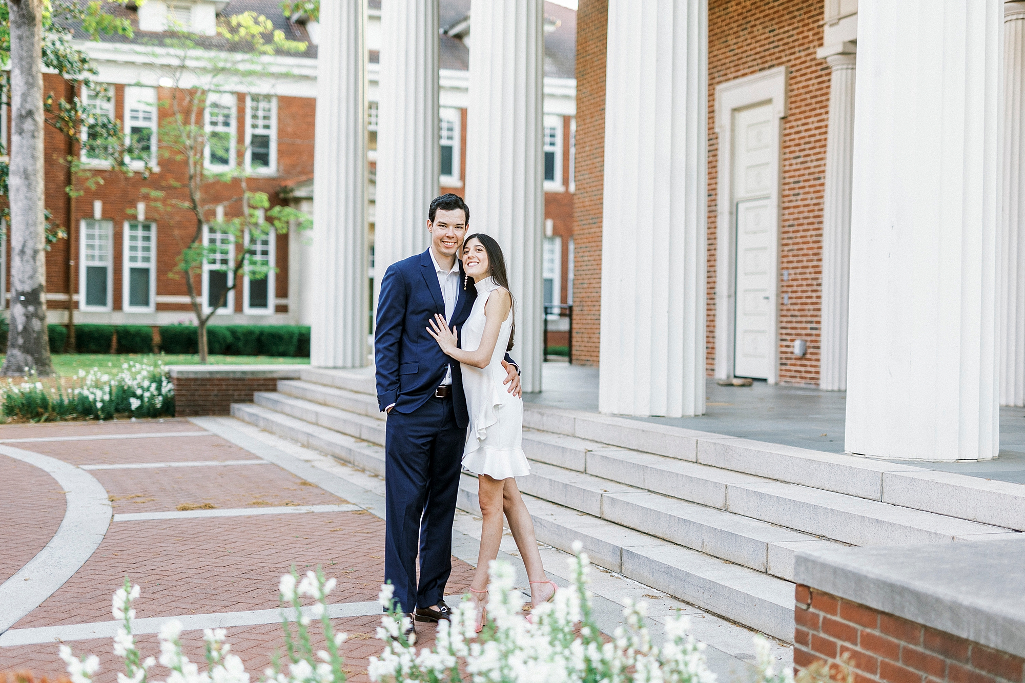 bride hugs groom looking up at him on patio at Queens University