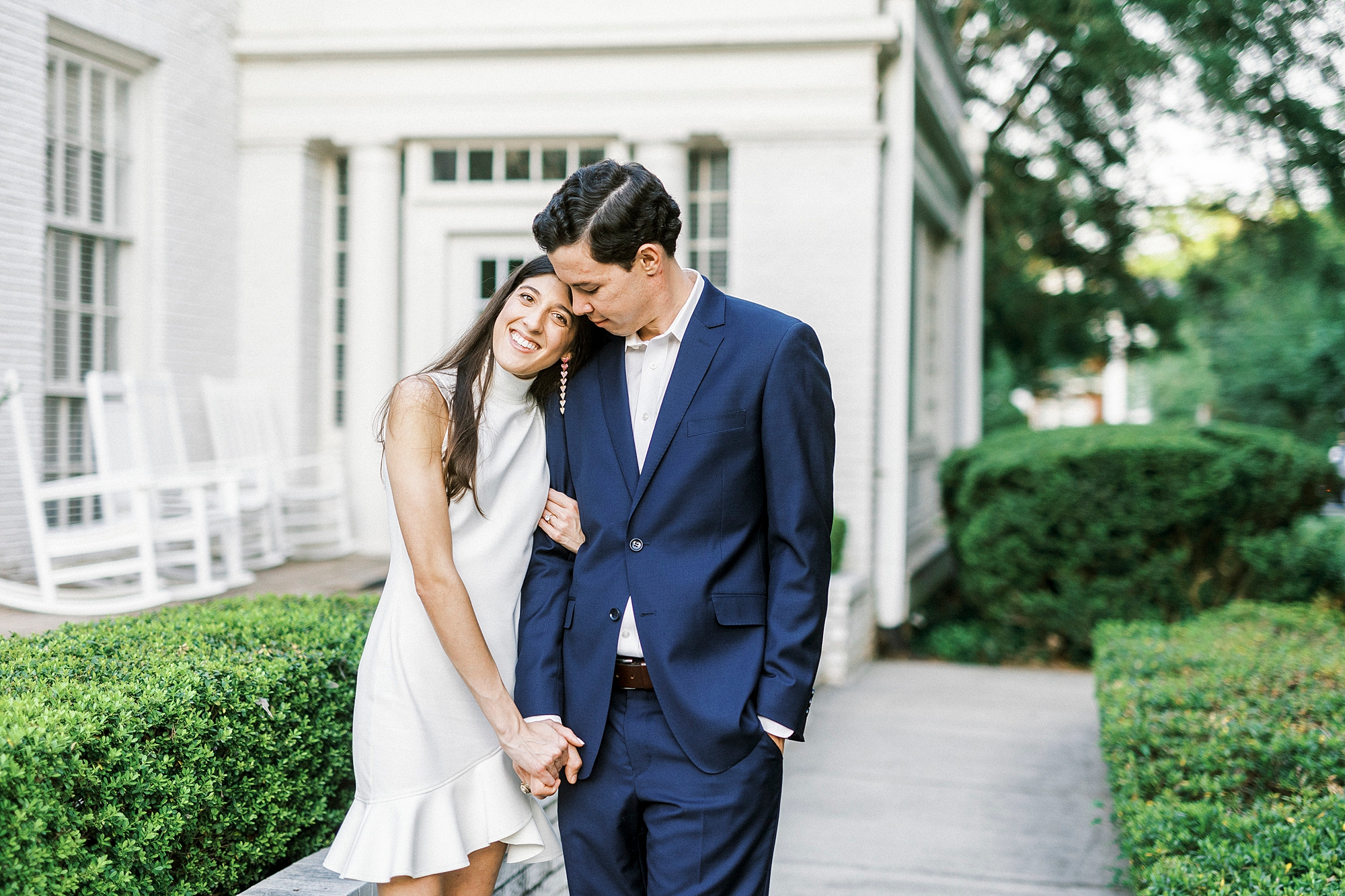 bride leans on groom's shoulder walking through buildings at Queens University