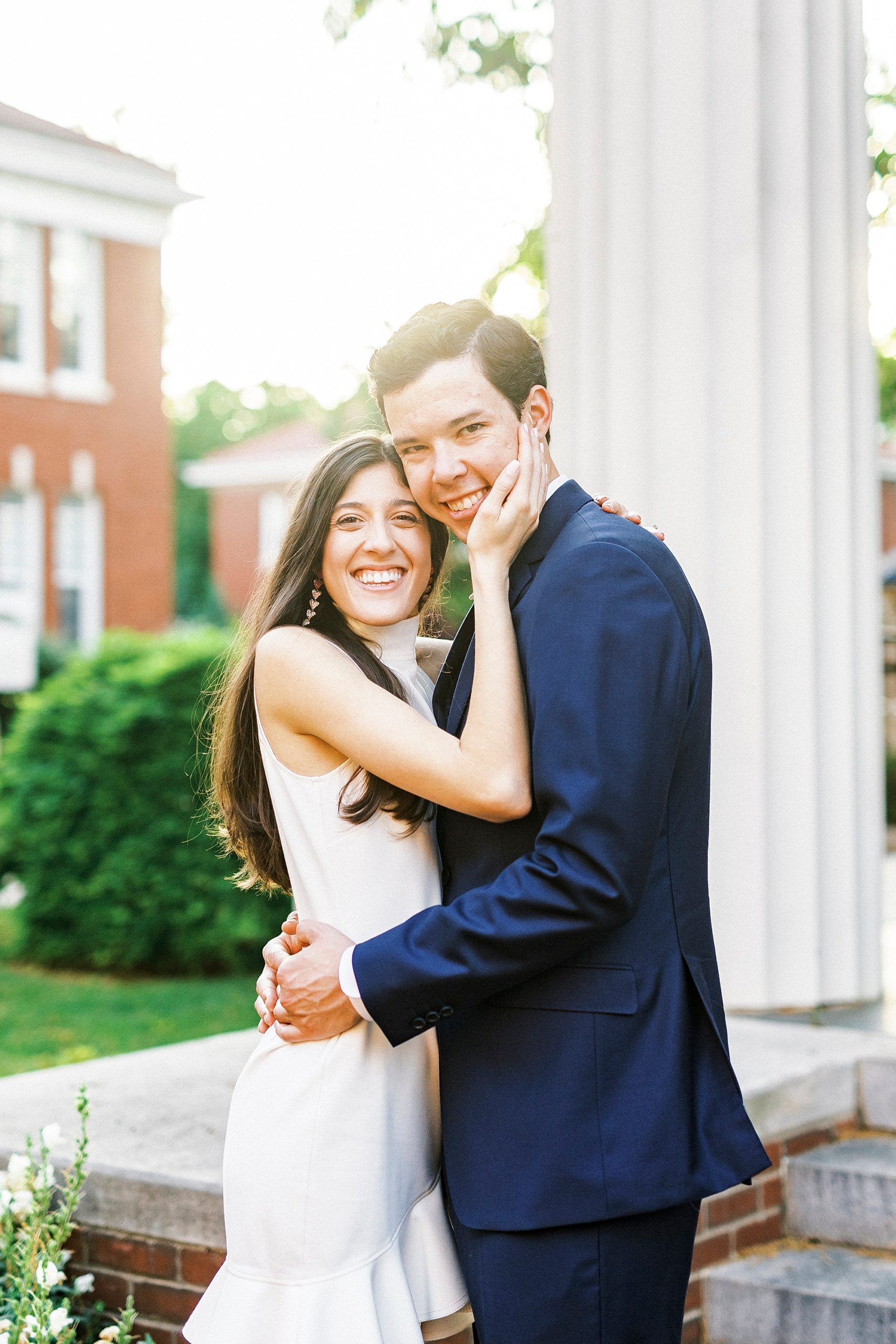 bride holds groom's face standing by pillar at Queens University