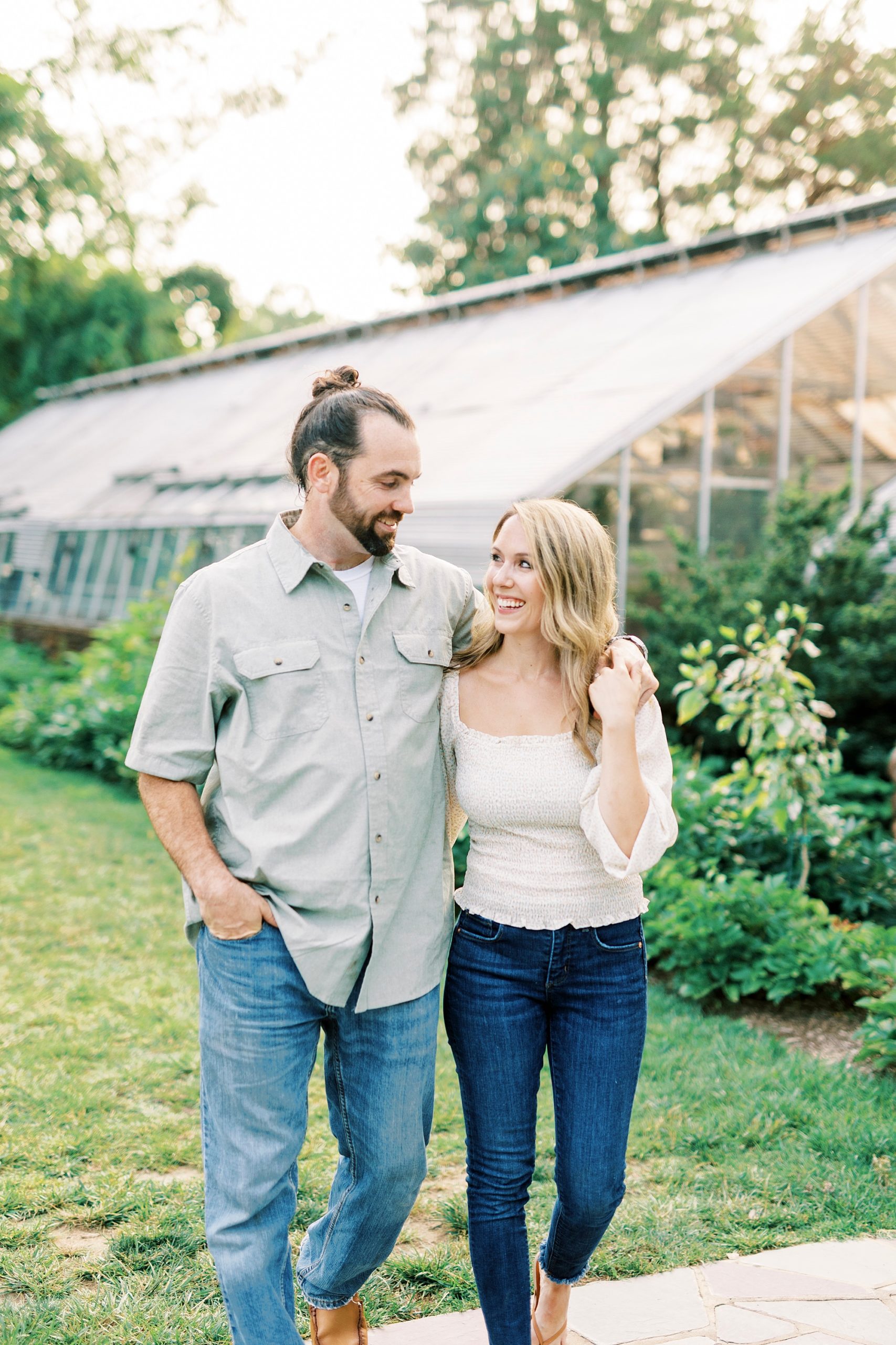 bride and groom walk together across lawn with arms around each other 