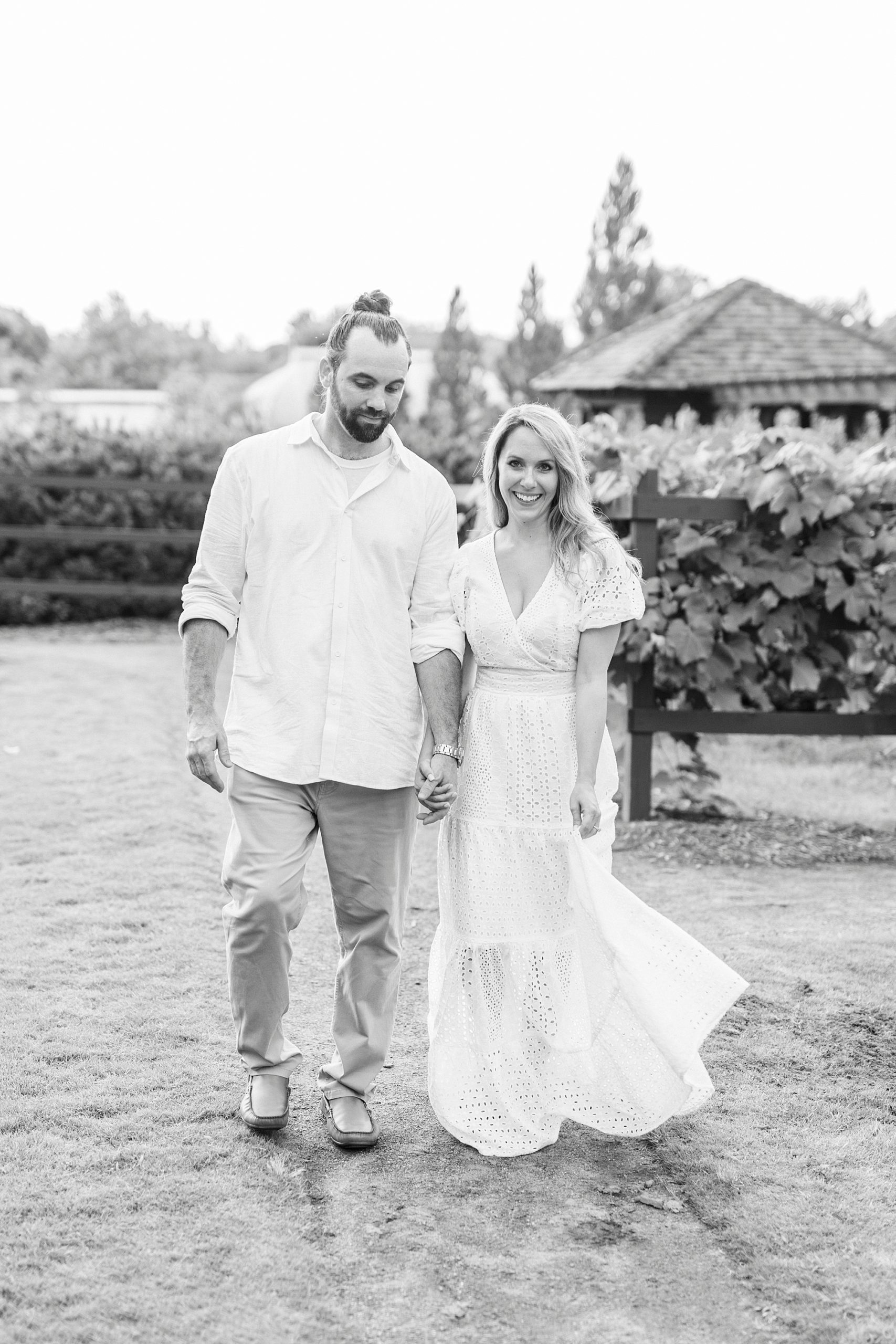 engaged couple holds hands walking through vines