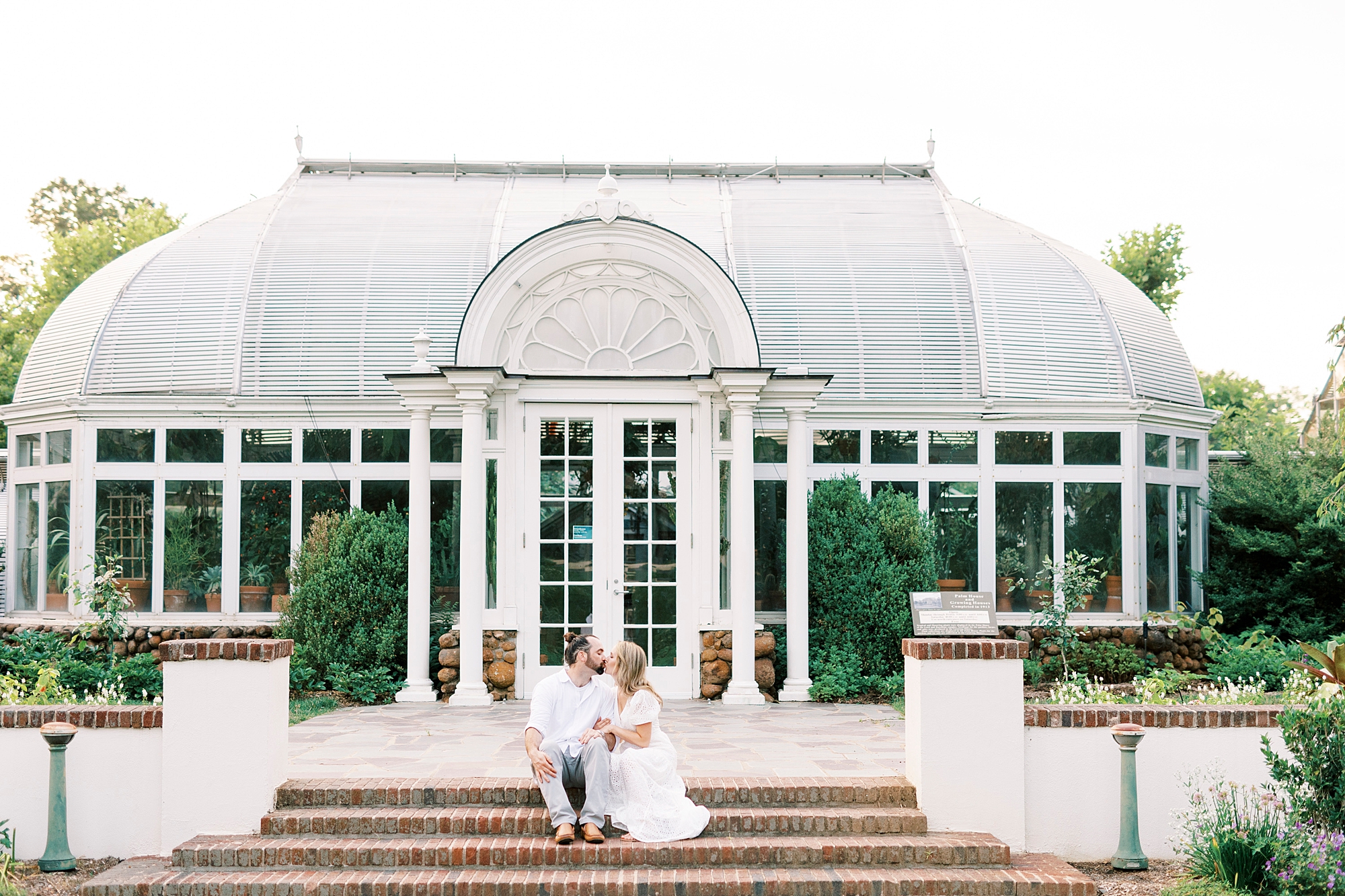bride and groom sit on brick steps outside building at Reynolda Gardens