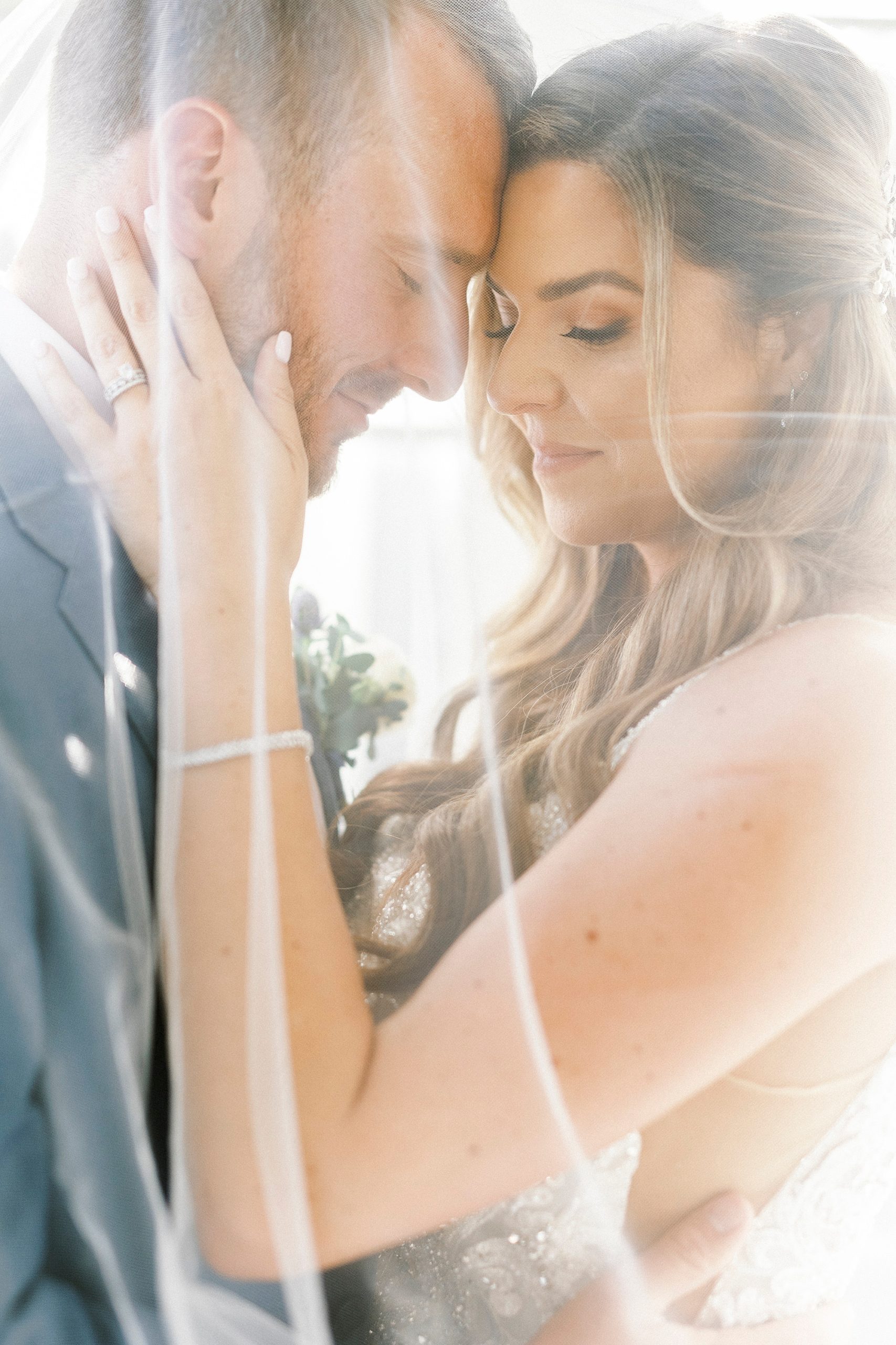 newlyweds hug under veil