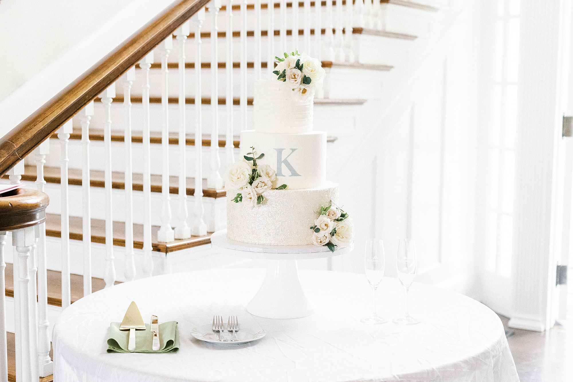 tiered wedding cake with floral accents and blue K on side