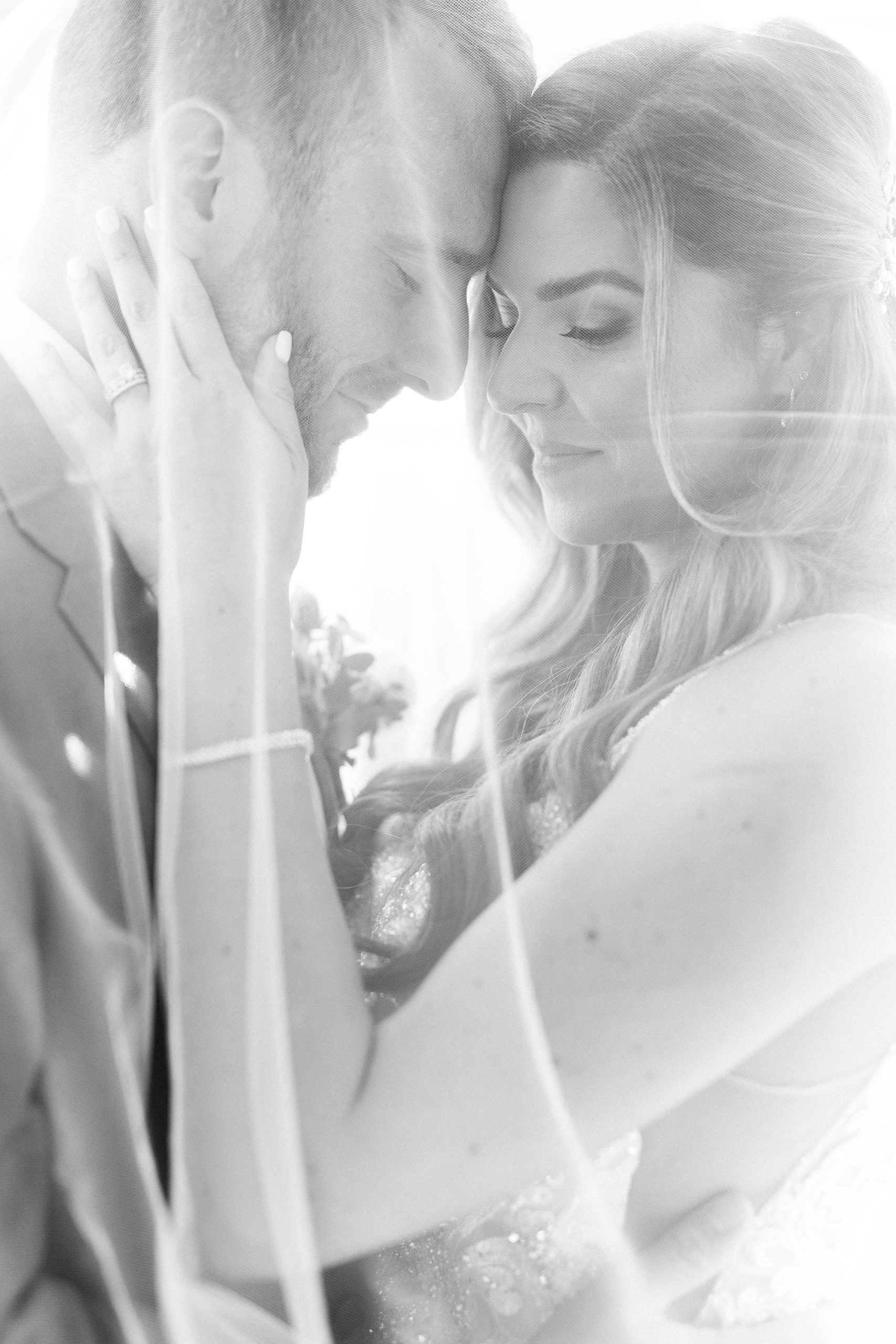bride and groom lean foreheads together under bride's veil