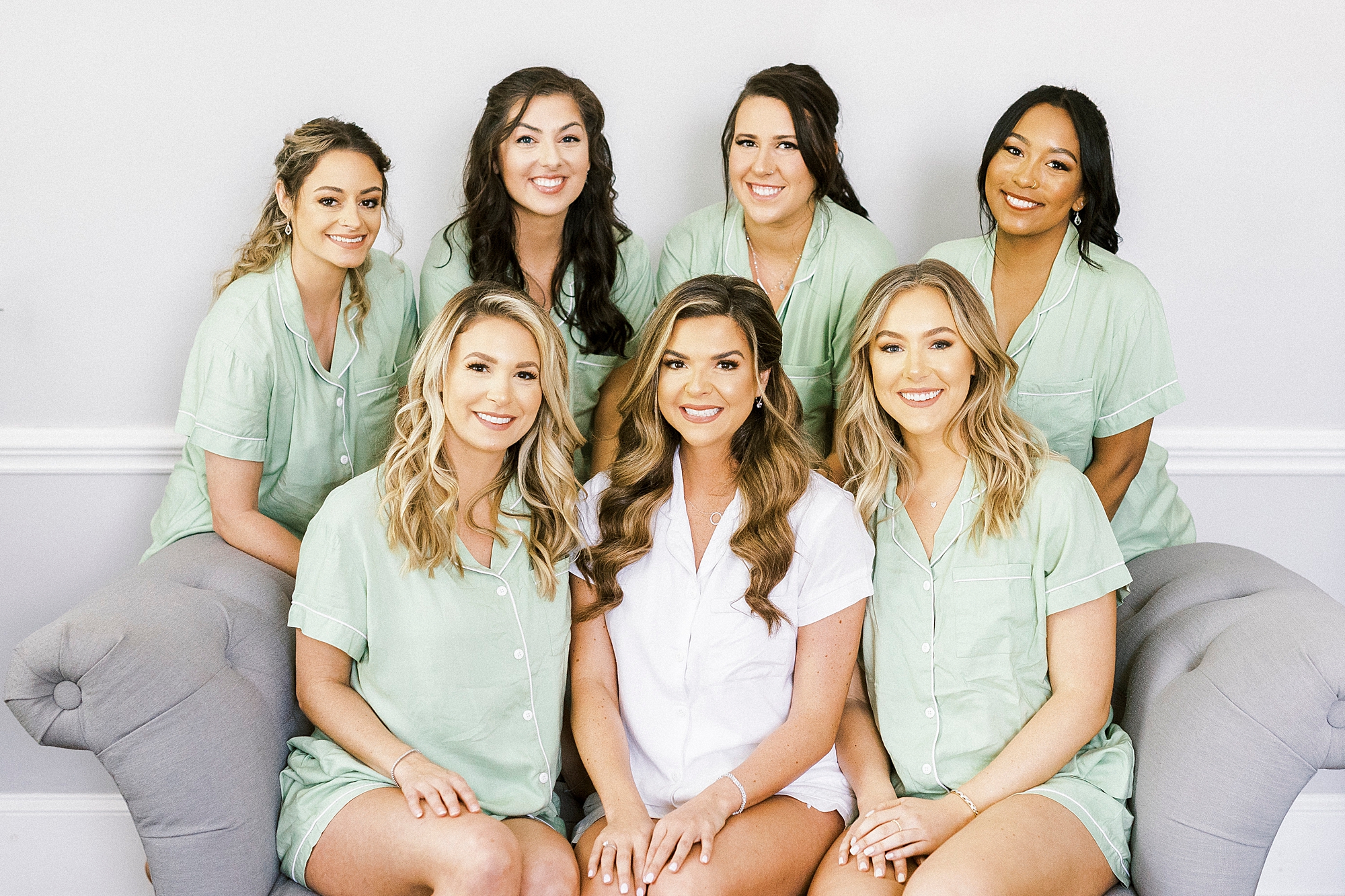 bride sits with bridesmaids in pale green pajamas