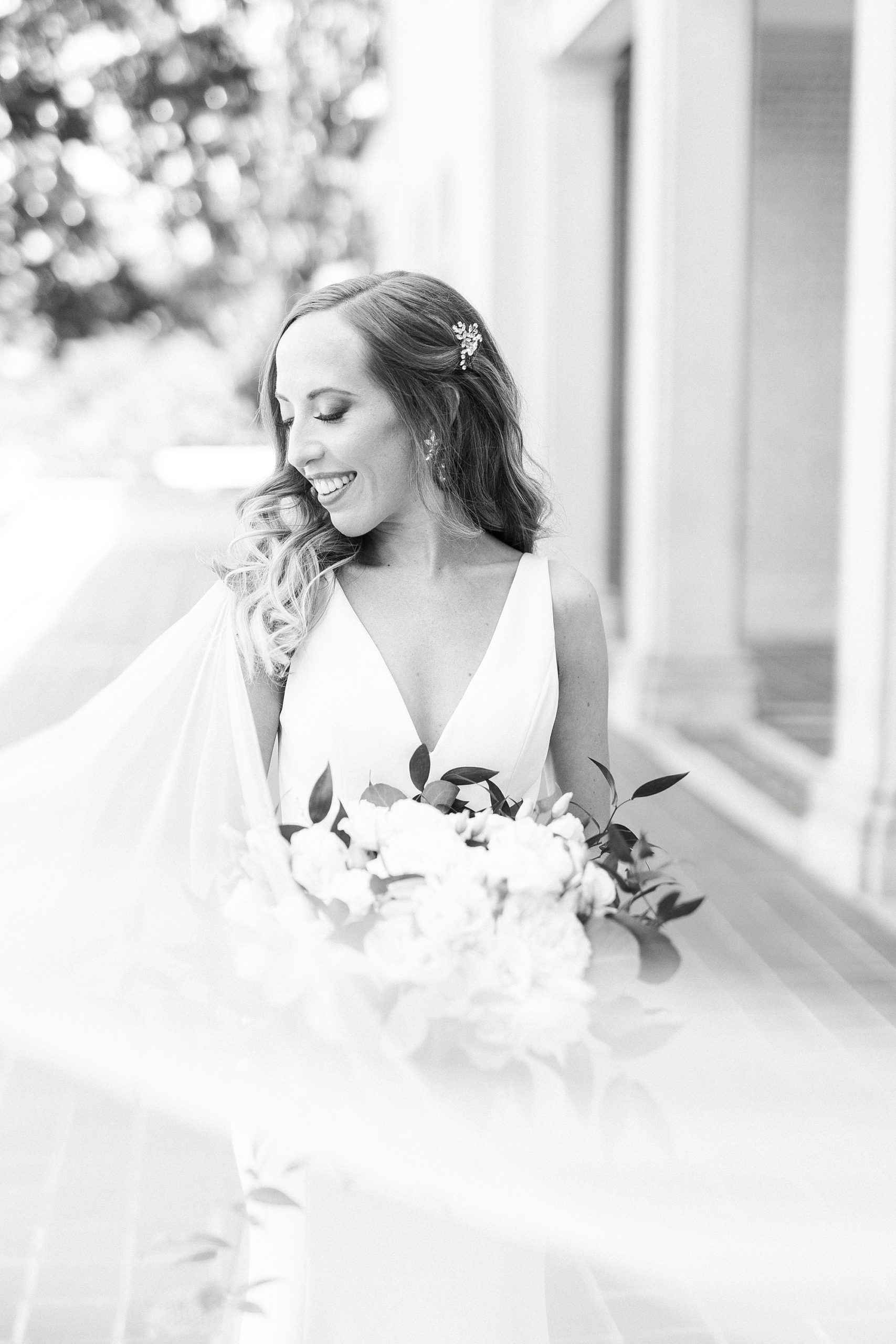 bride stands holding bouquet with veil around her