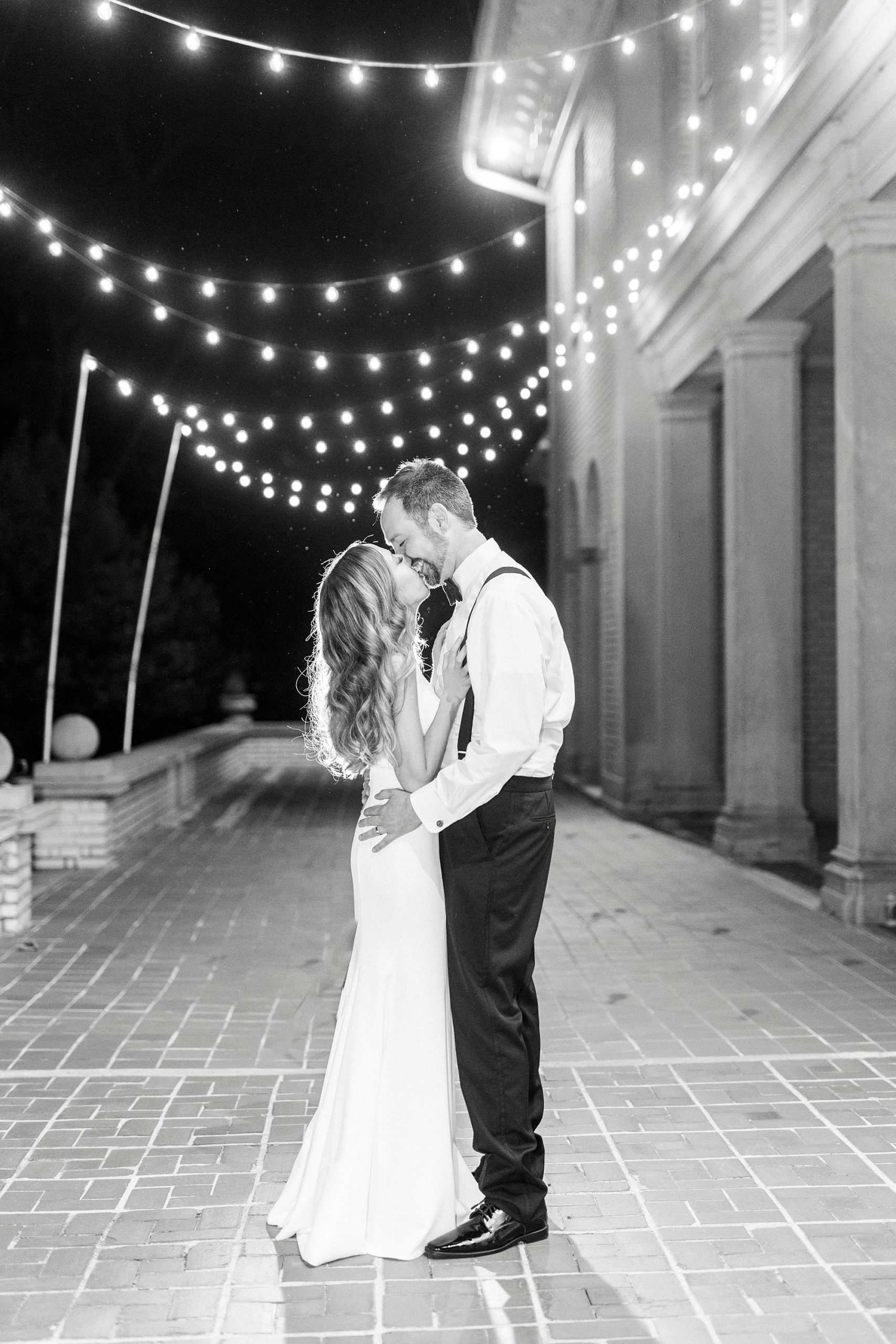 newlyweds kiss under patio lights at Separk Mansion in the dark