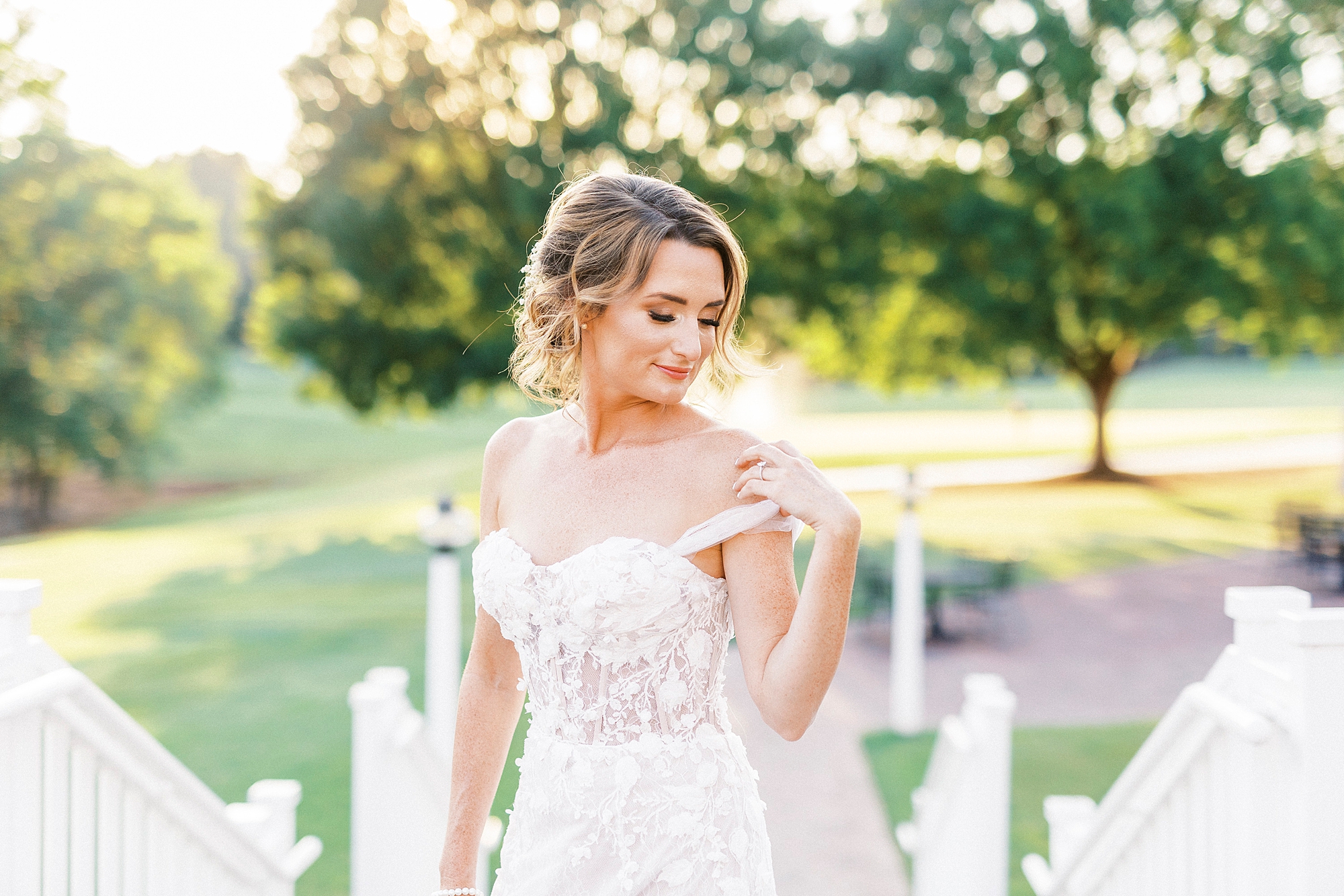 bride holds strap of wedding gown on shoulder during Trump National Golf Club bridal portraits