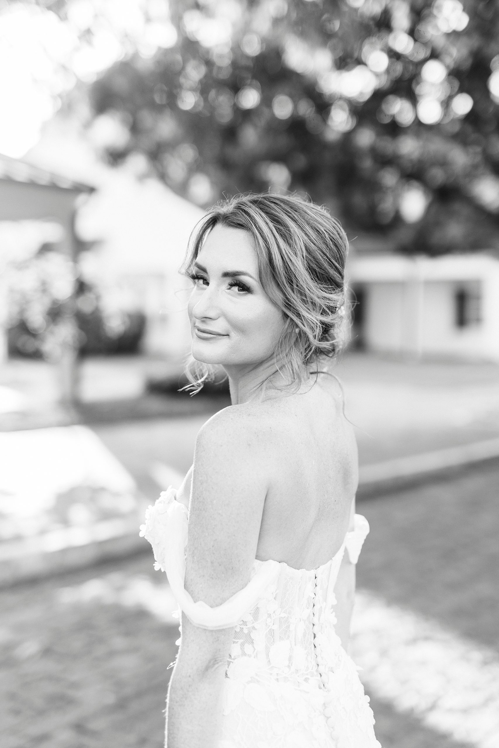 bride smirks over shoulder in off-the-shoulder wedding gown