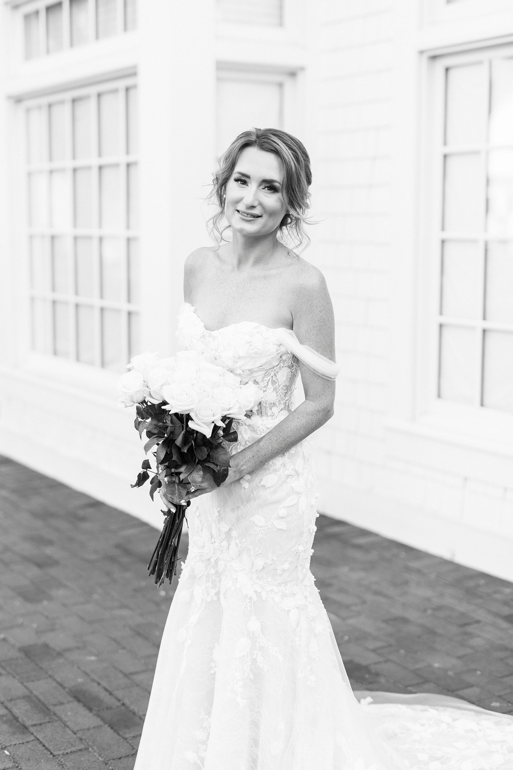 bride leans forward slightly holding bouquet of white flowers 