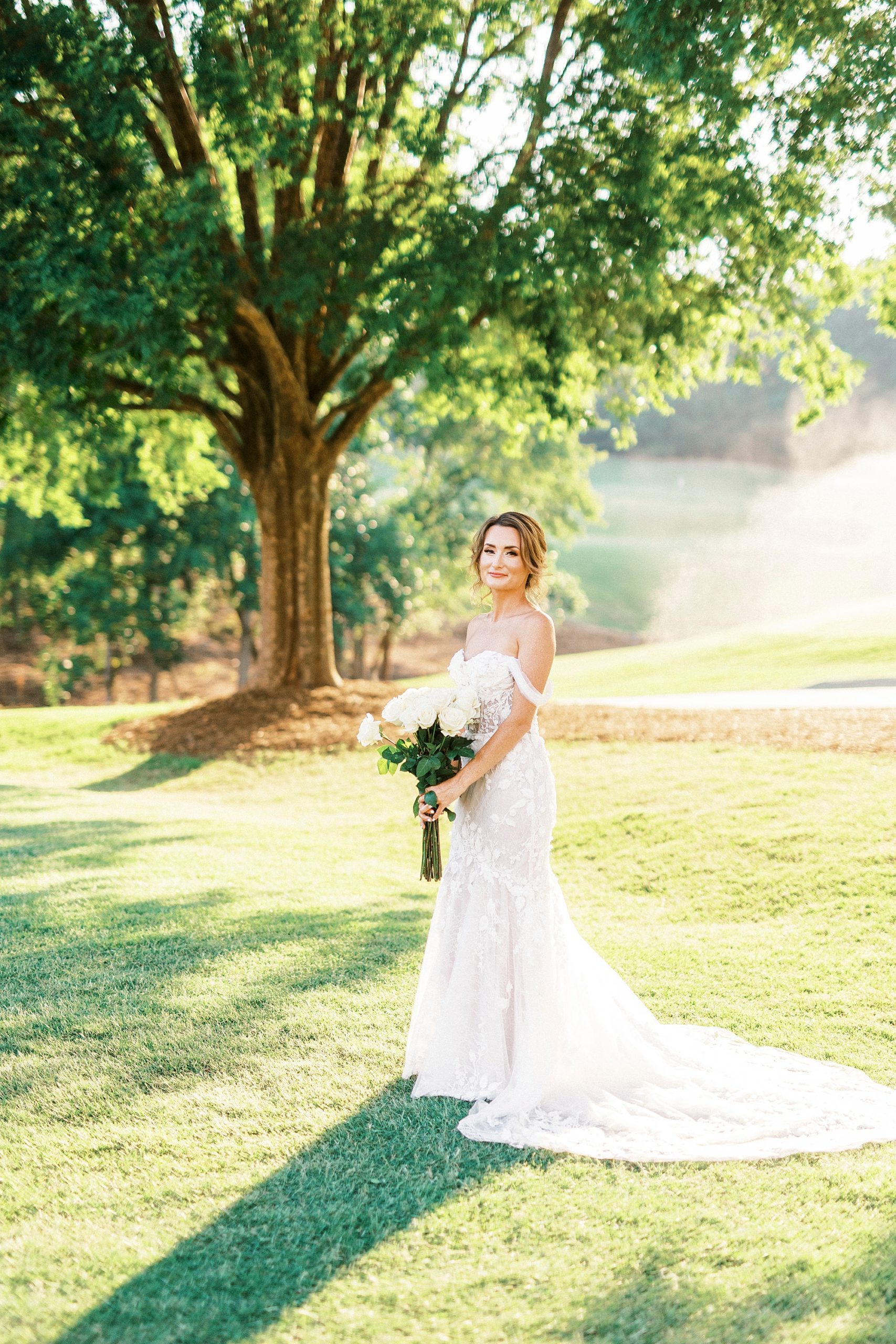 bride stands holding all-white bouquet during Trump National Golf Club bridal portraits