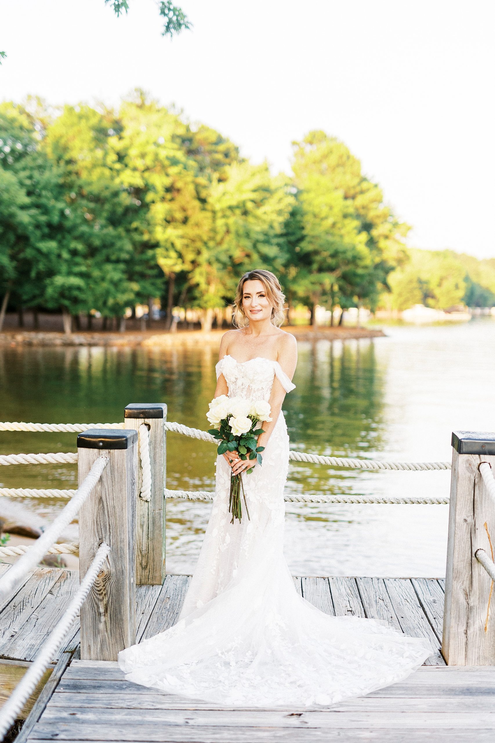 bride stands holding bouquet of white roses during Trump National Golf Club bridal portraits 