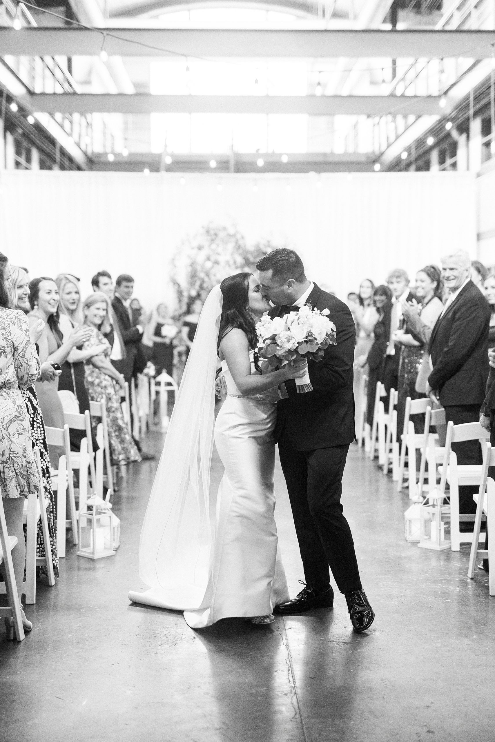 bride and groom kiss after walking up aisle at Design Atrium