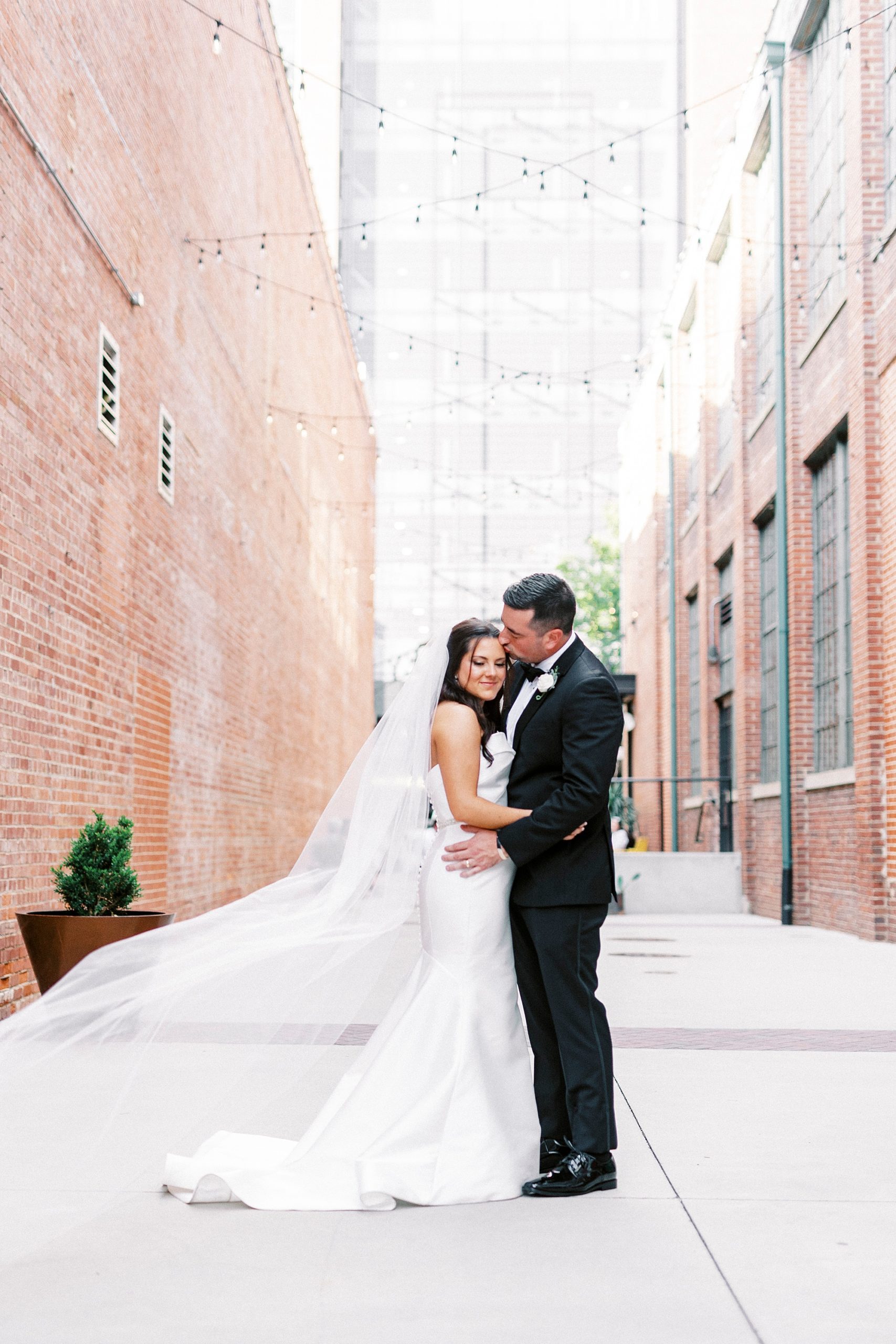 groom kisses bride's cheek in alleyway outside Byron's South End