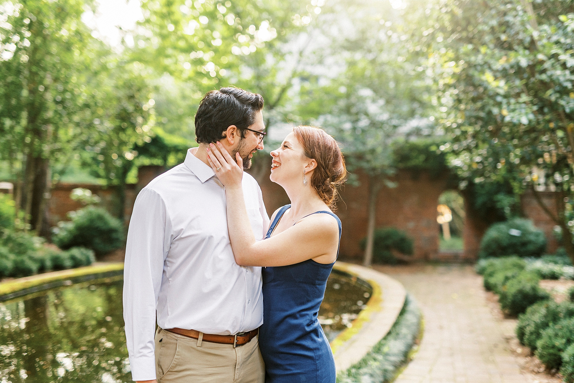 woman holds man's face with hands during photos in gardens in NC