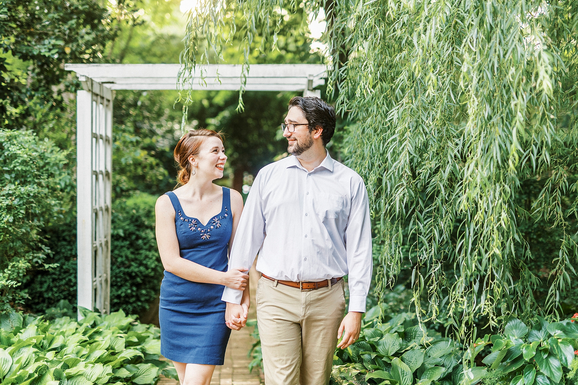 married couple holds hands walking through Wing Haven Garden