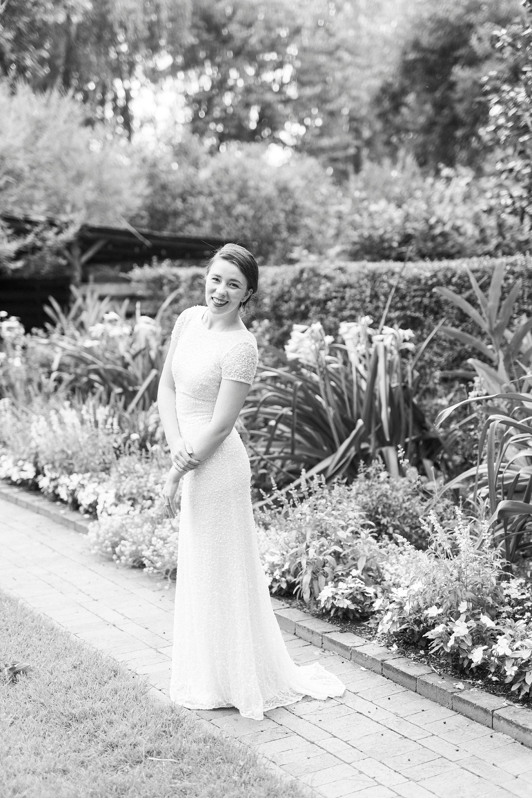 wife stands in long wedding gown at Wing Haven Garden