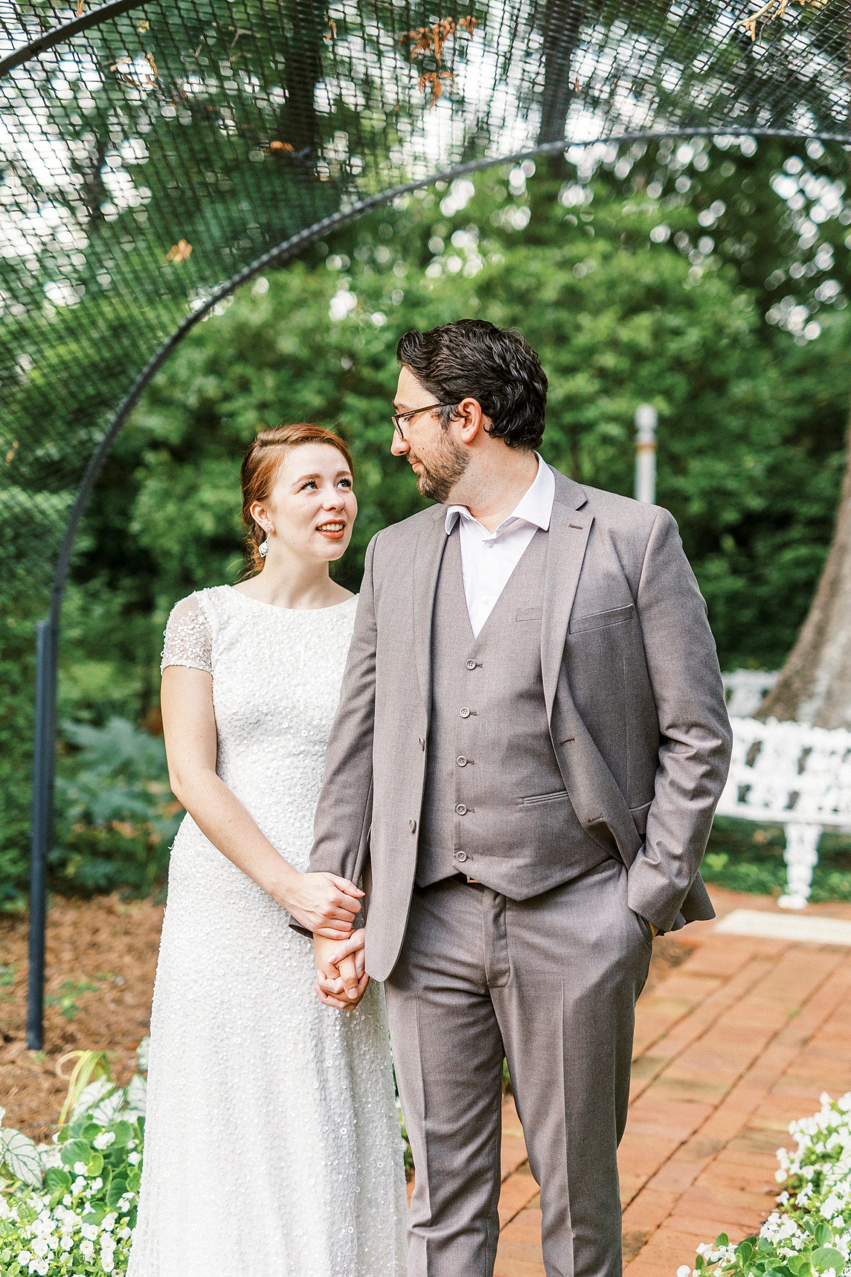 married couple holds hands walking through Wing Haven Garden