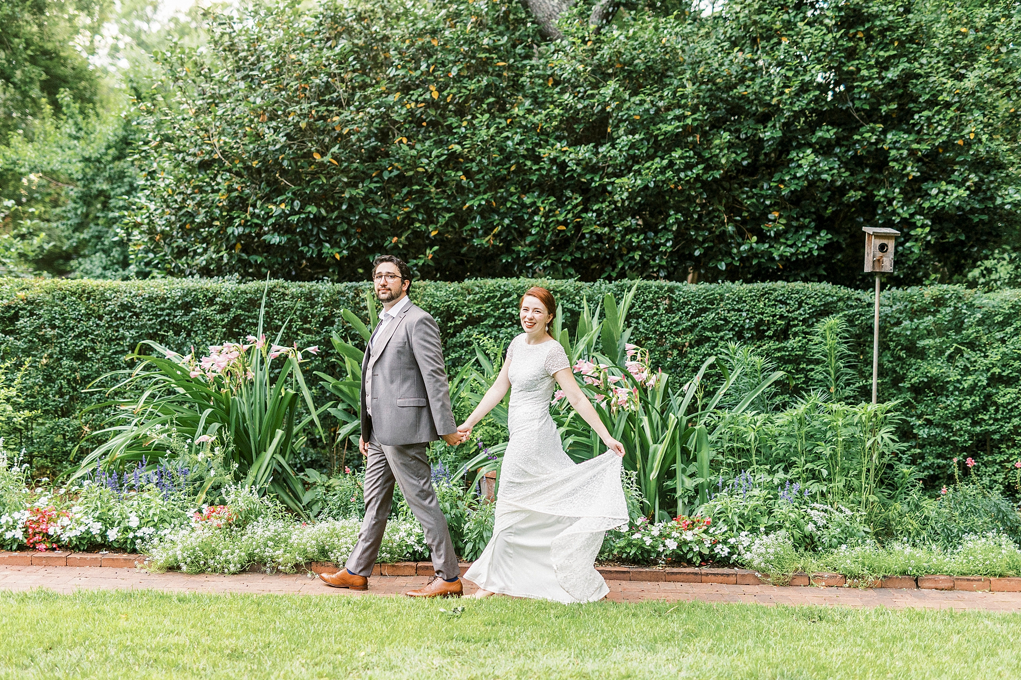 couple holds hands walking through Wing Haven Garden