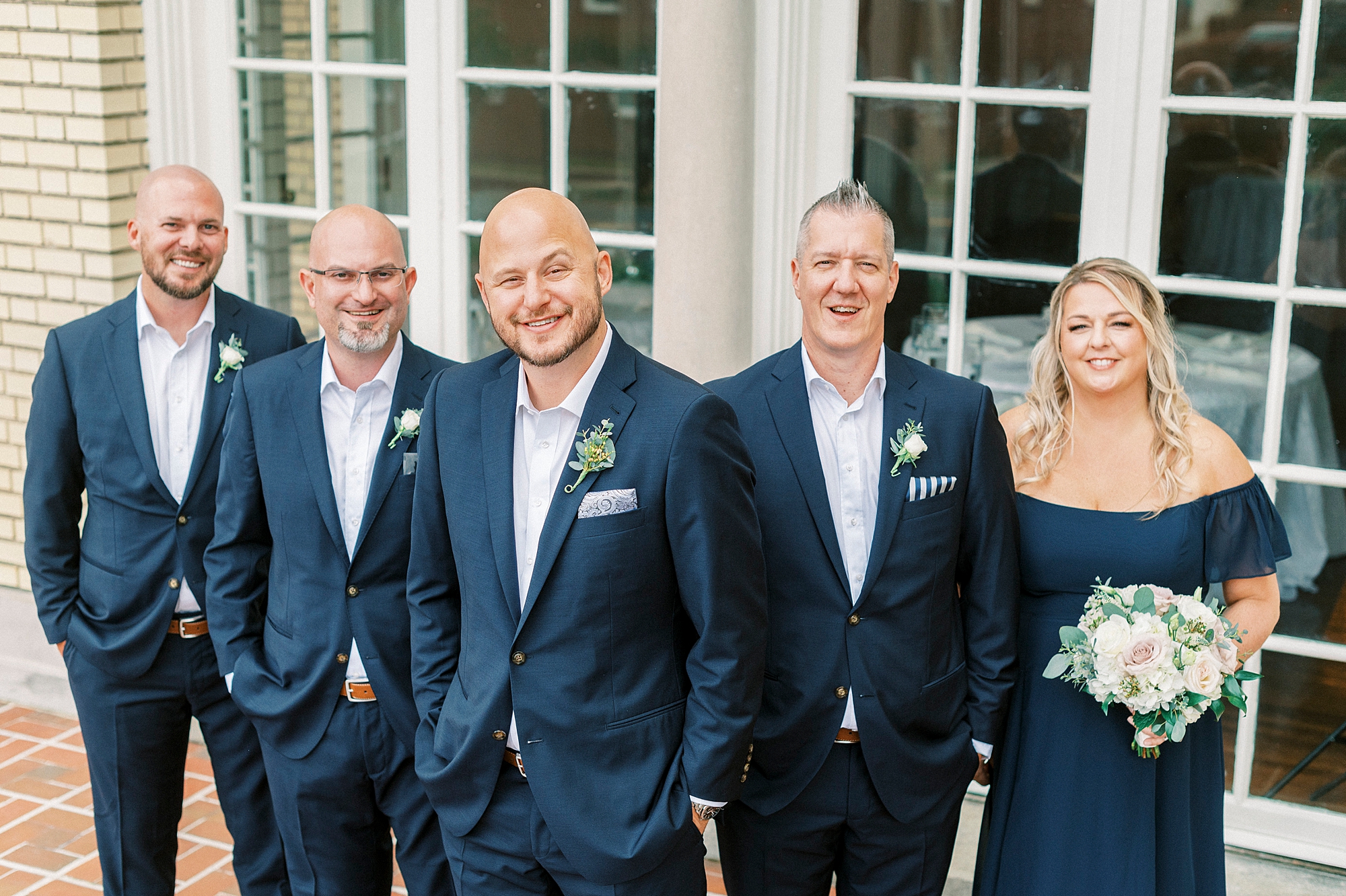 groom stands with wedding party in navy outside Separk Mansion