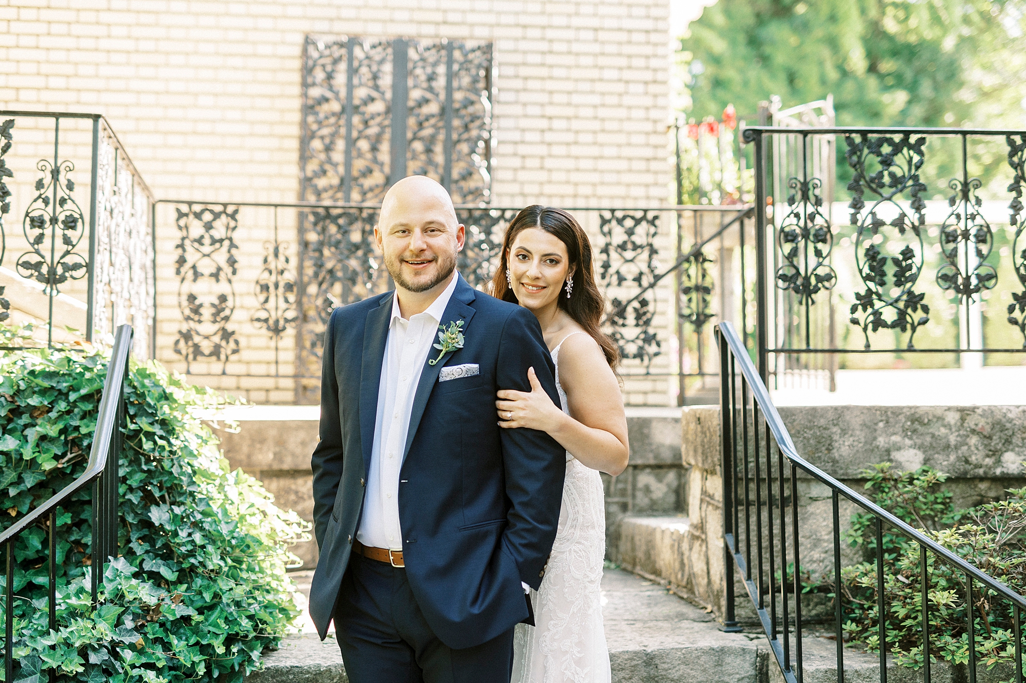 bride hugs groom from behind standing on steps at Separk Mansion