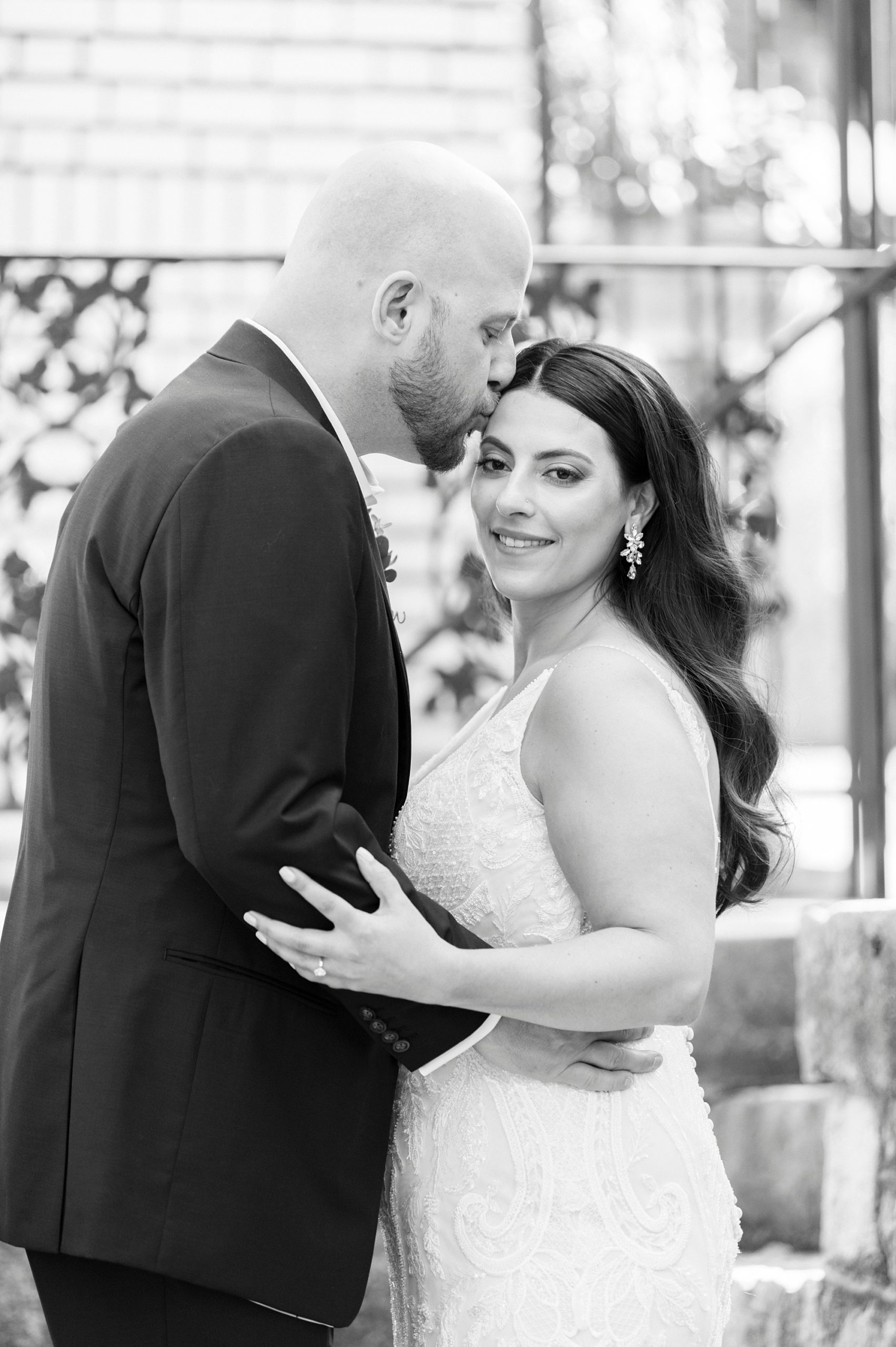 groom hugs bride and kisses her forehead