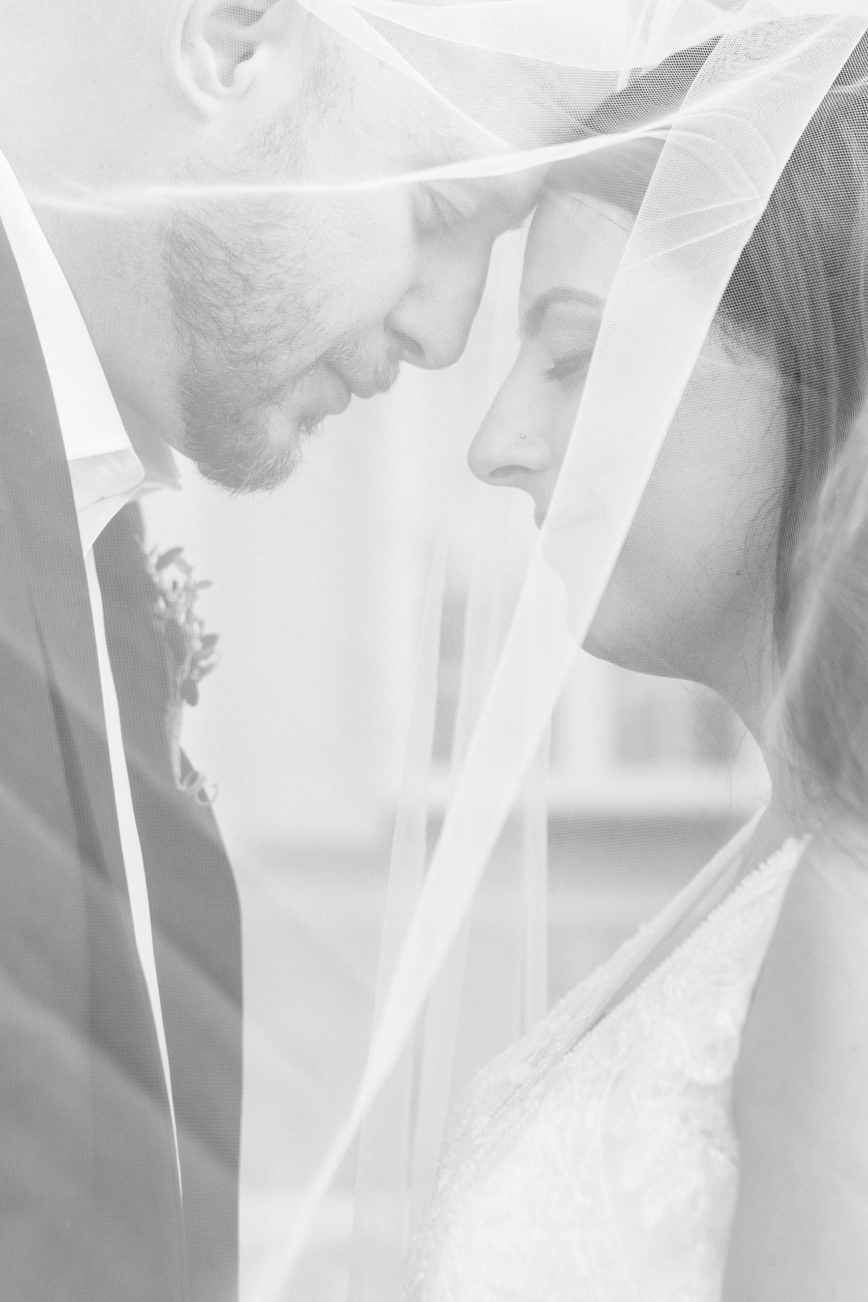 bride and groom lean heads together under veil