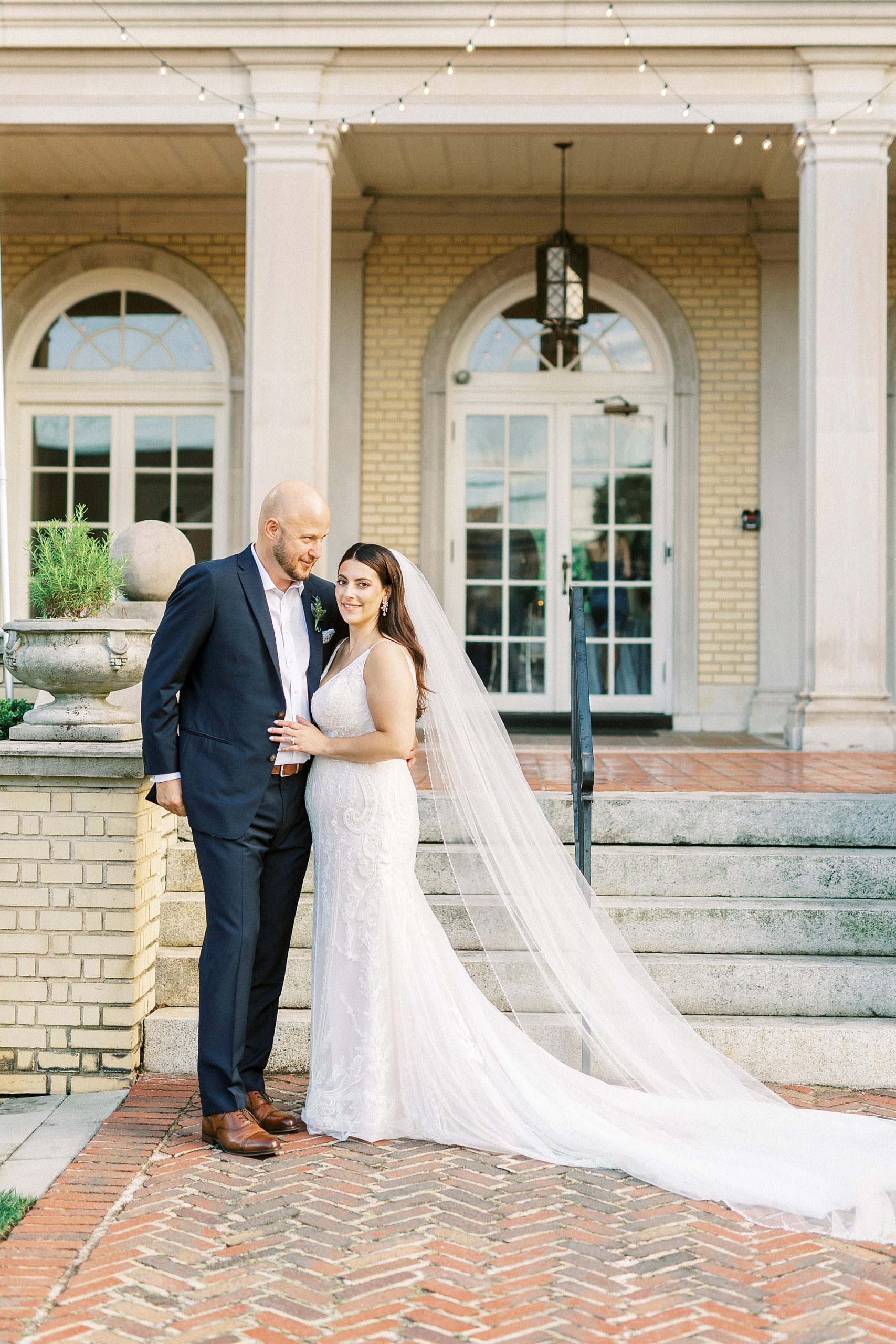 husband and wife stand outside mansion in Charlotte NC