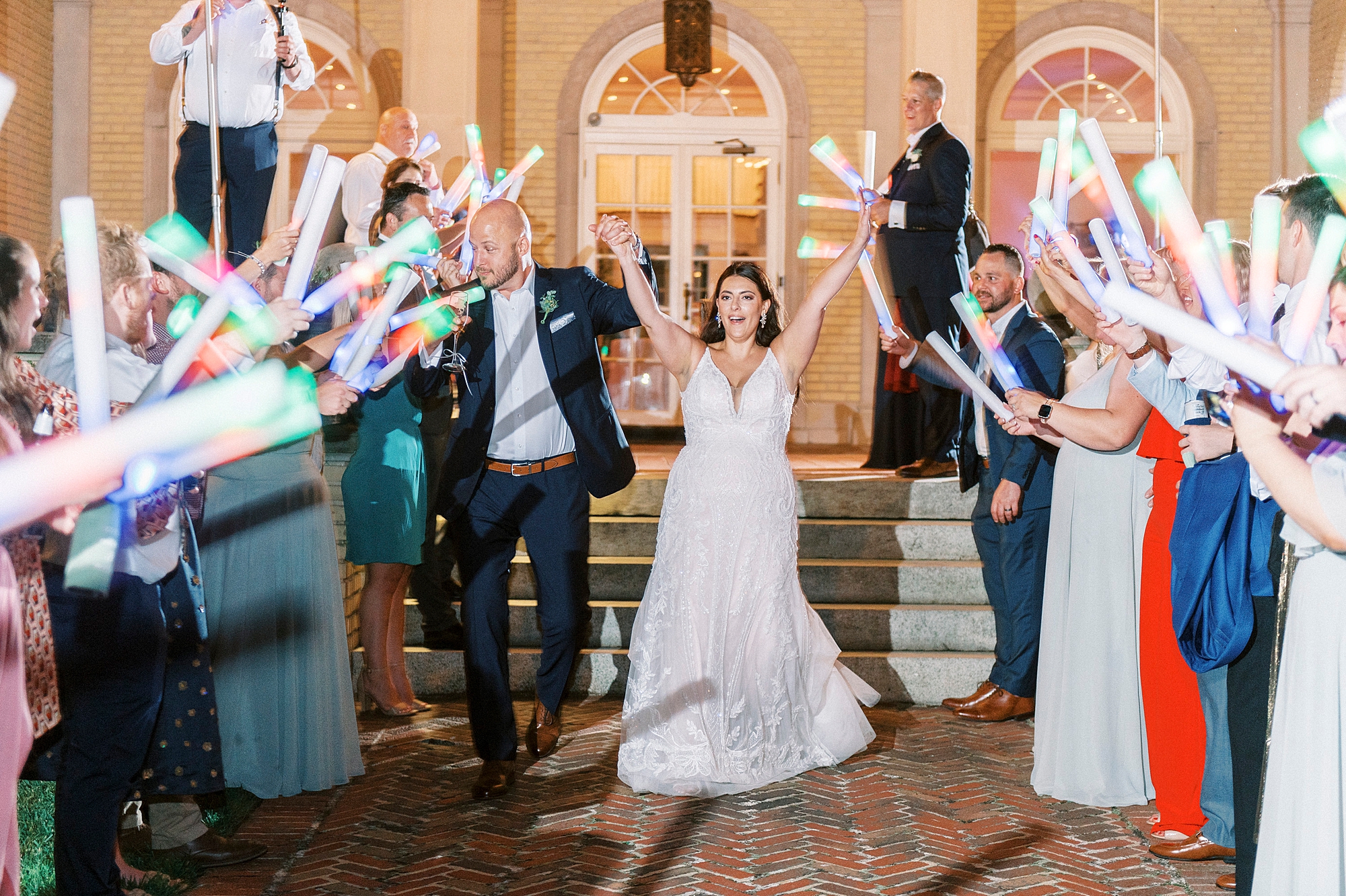 bride and groom cheer leaving NC wedding reception through glow stick exit